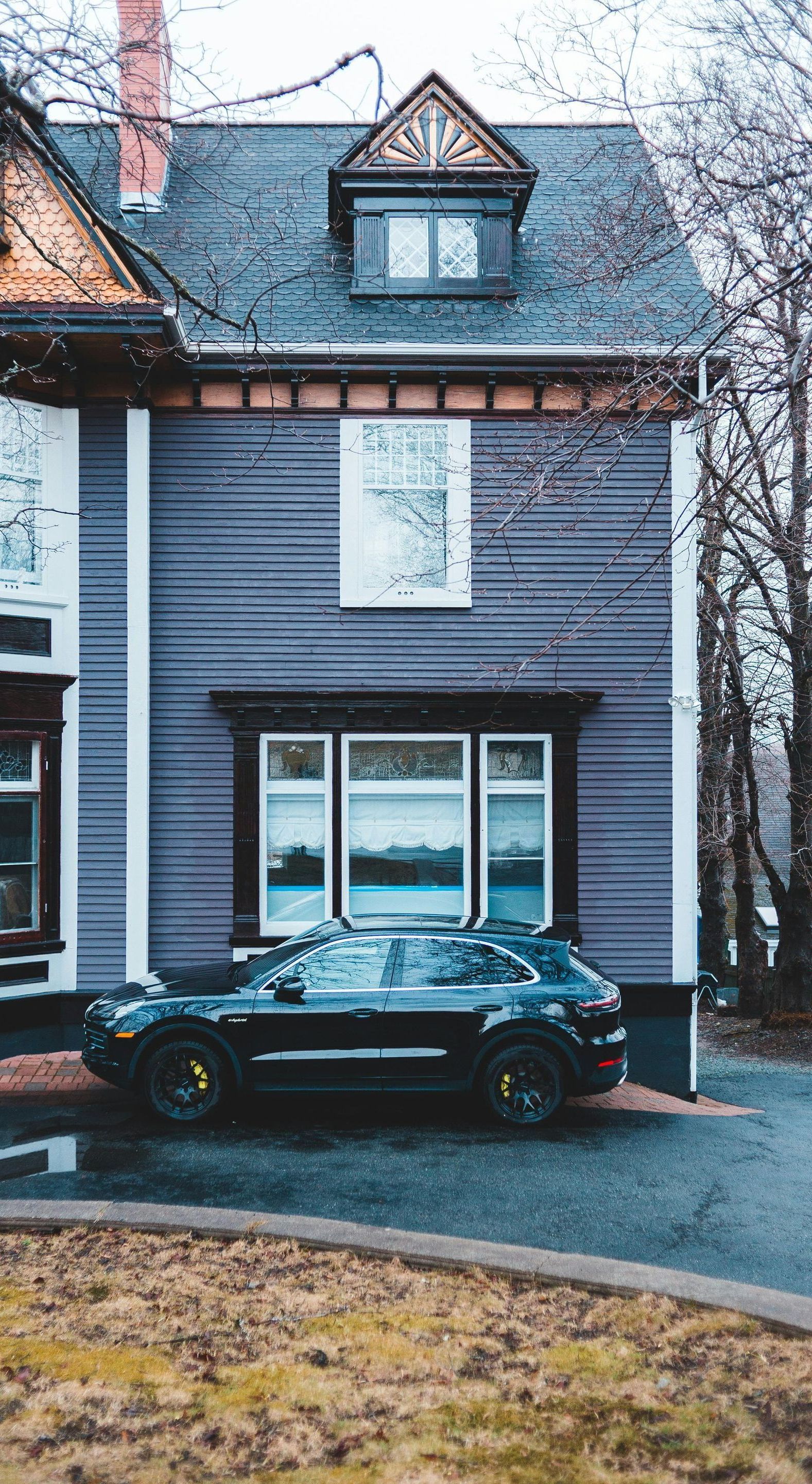 A black car is parked in front of a purple house.