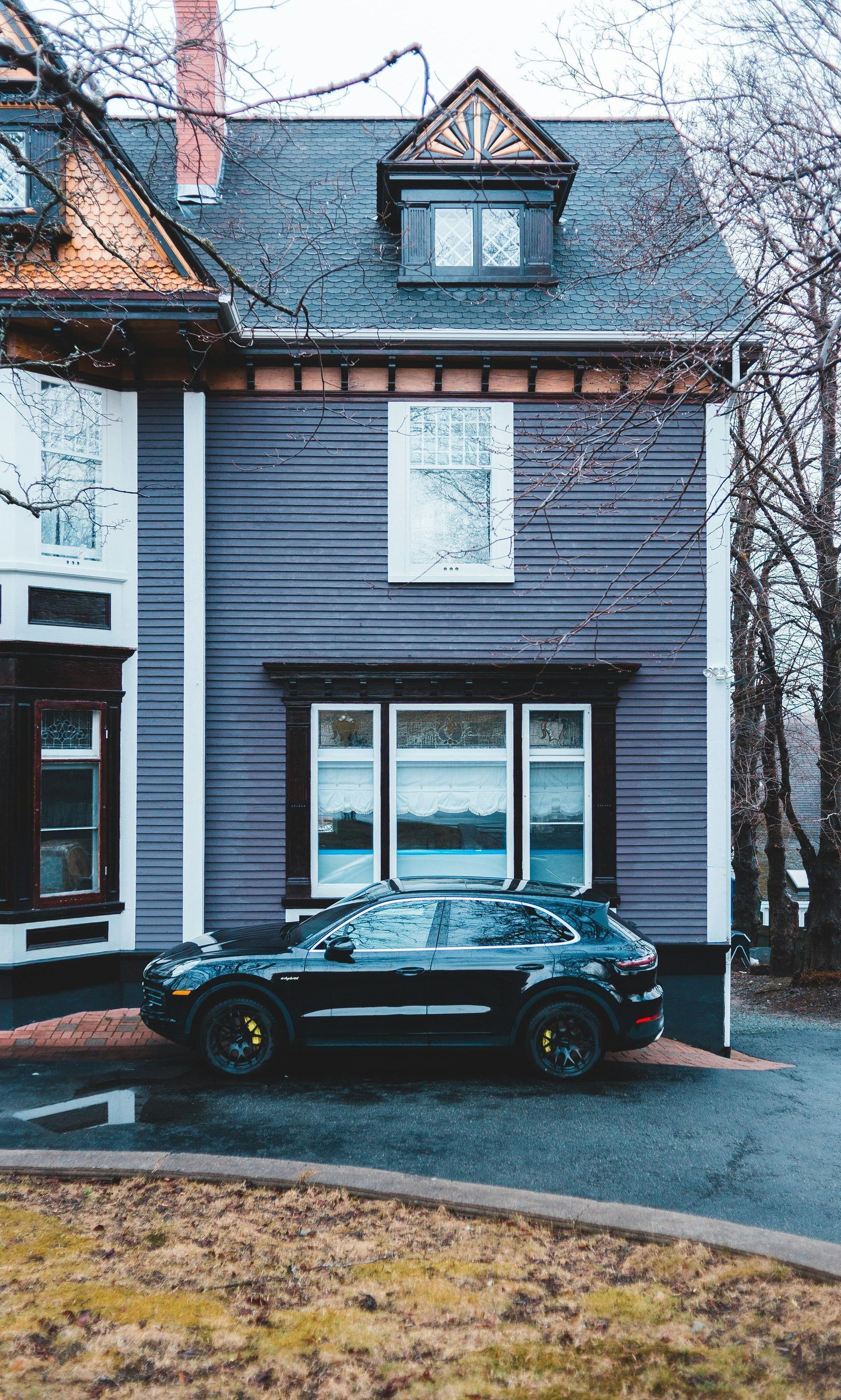 A black car is parked in front of a purple house.