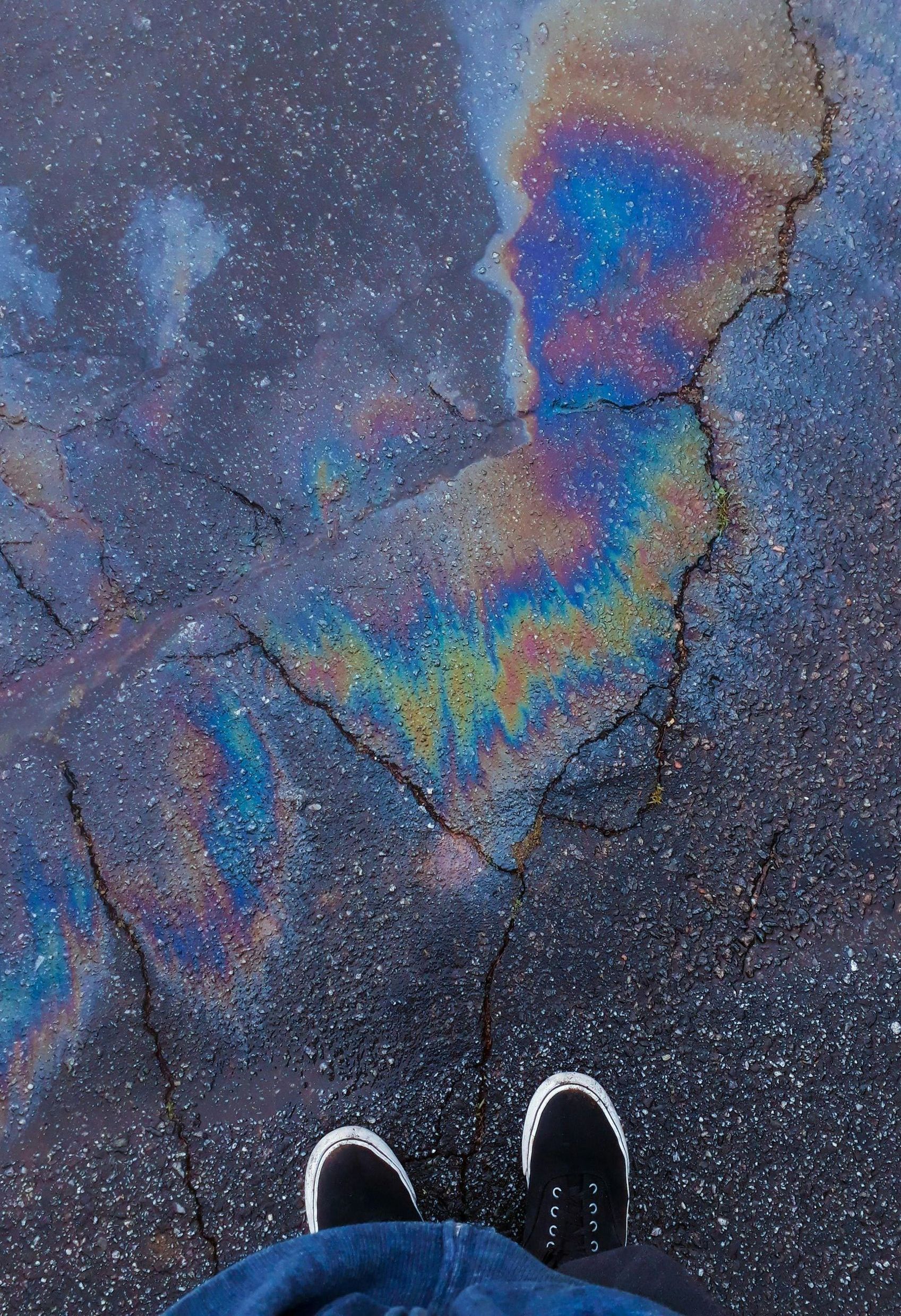 A person is standing in front of a puddle of oil on the ground.