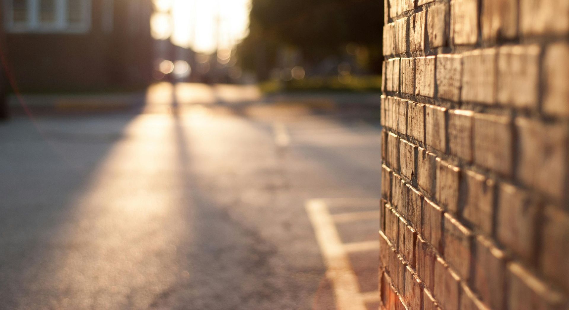 A close up of a brick wall with a street in the background.