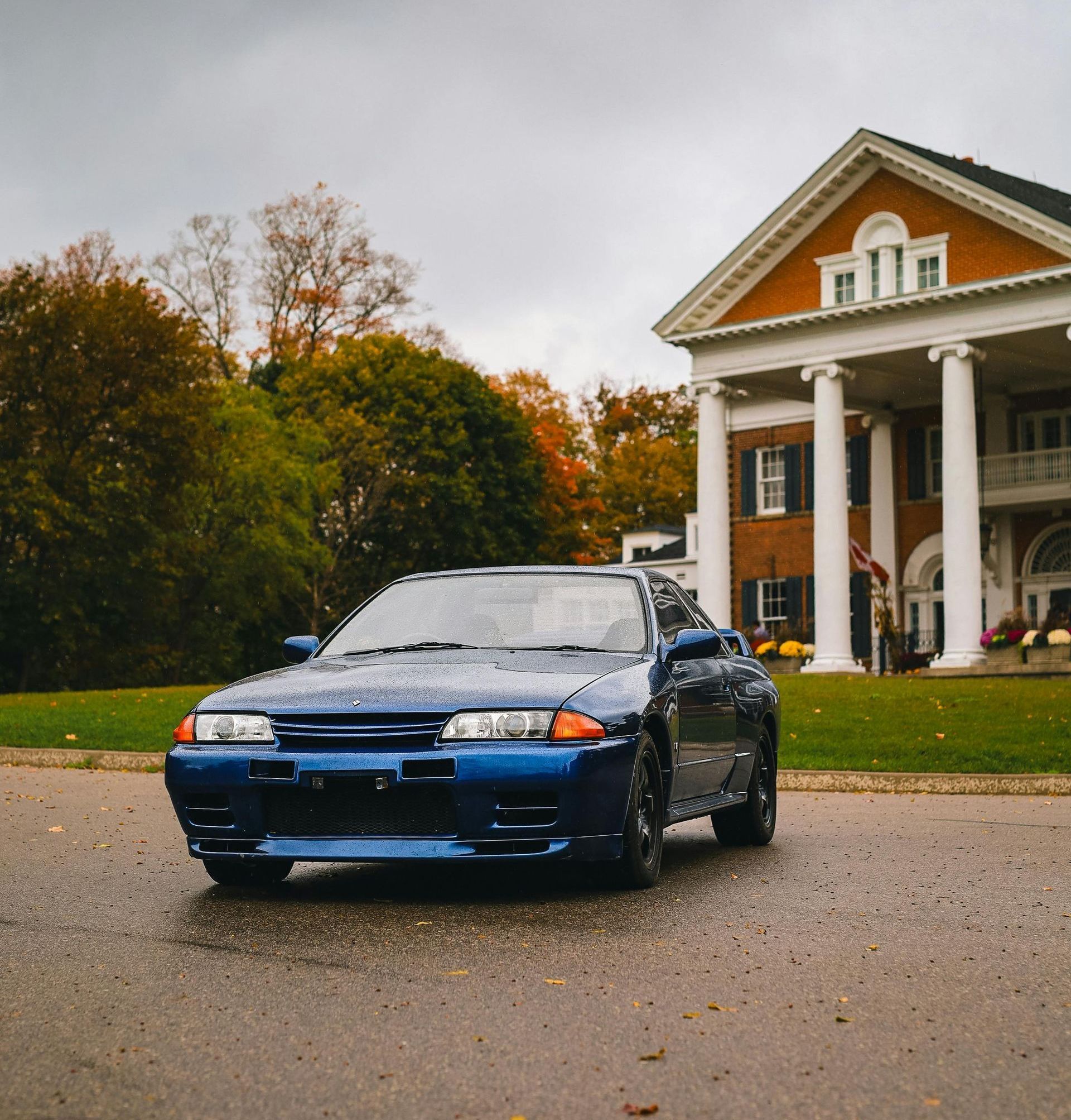 A blue car is parked in front of a large building