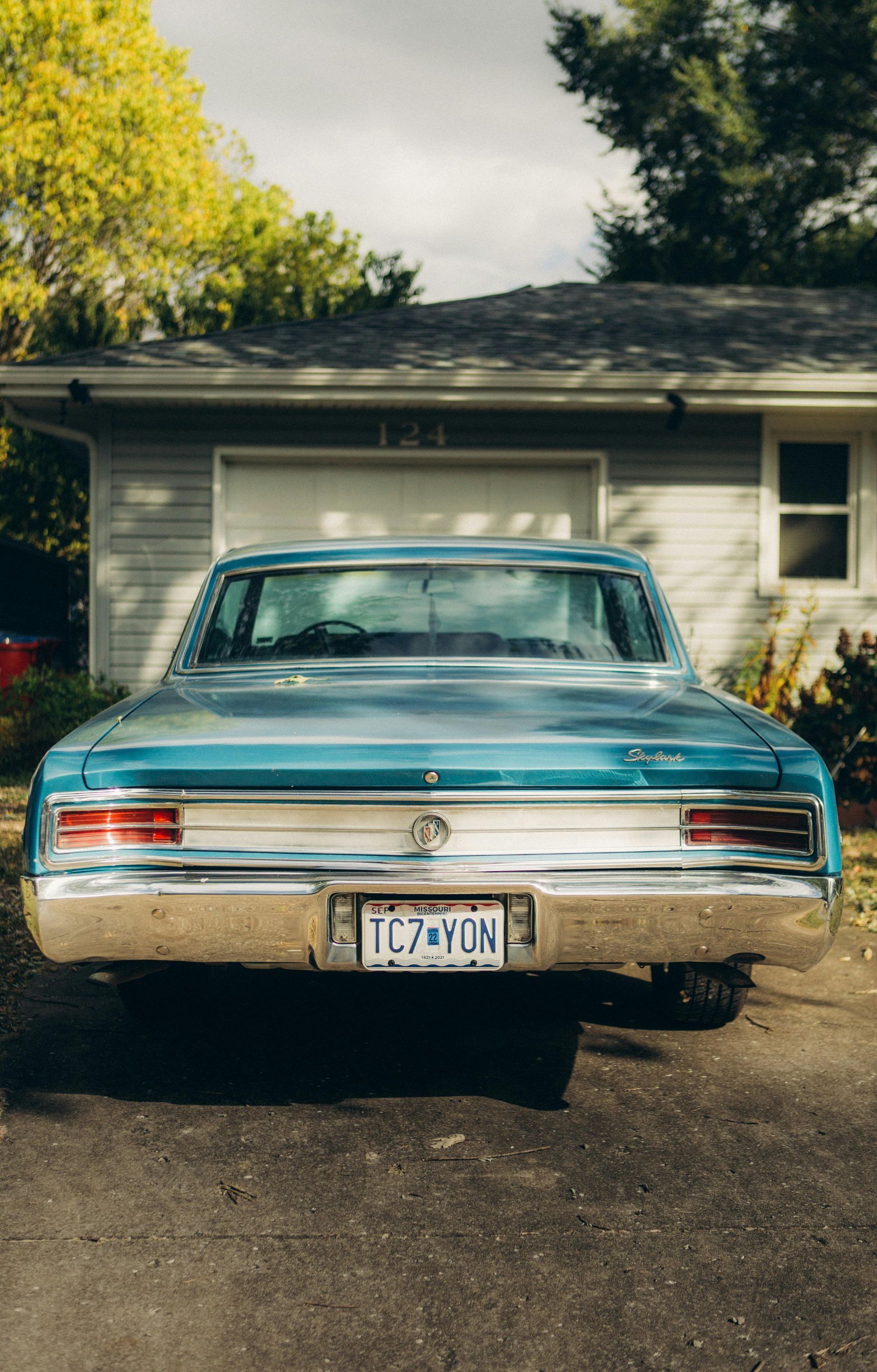 A blue car is parked in front of a house.