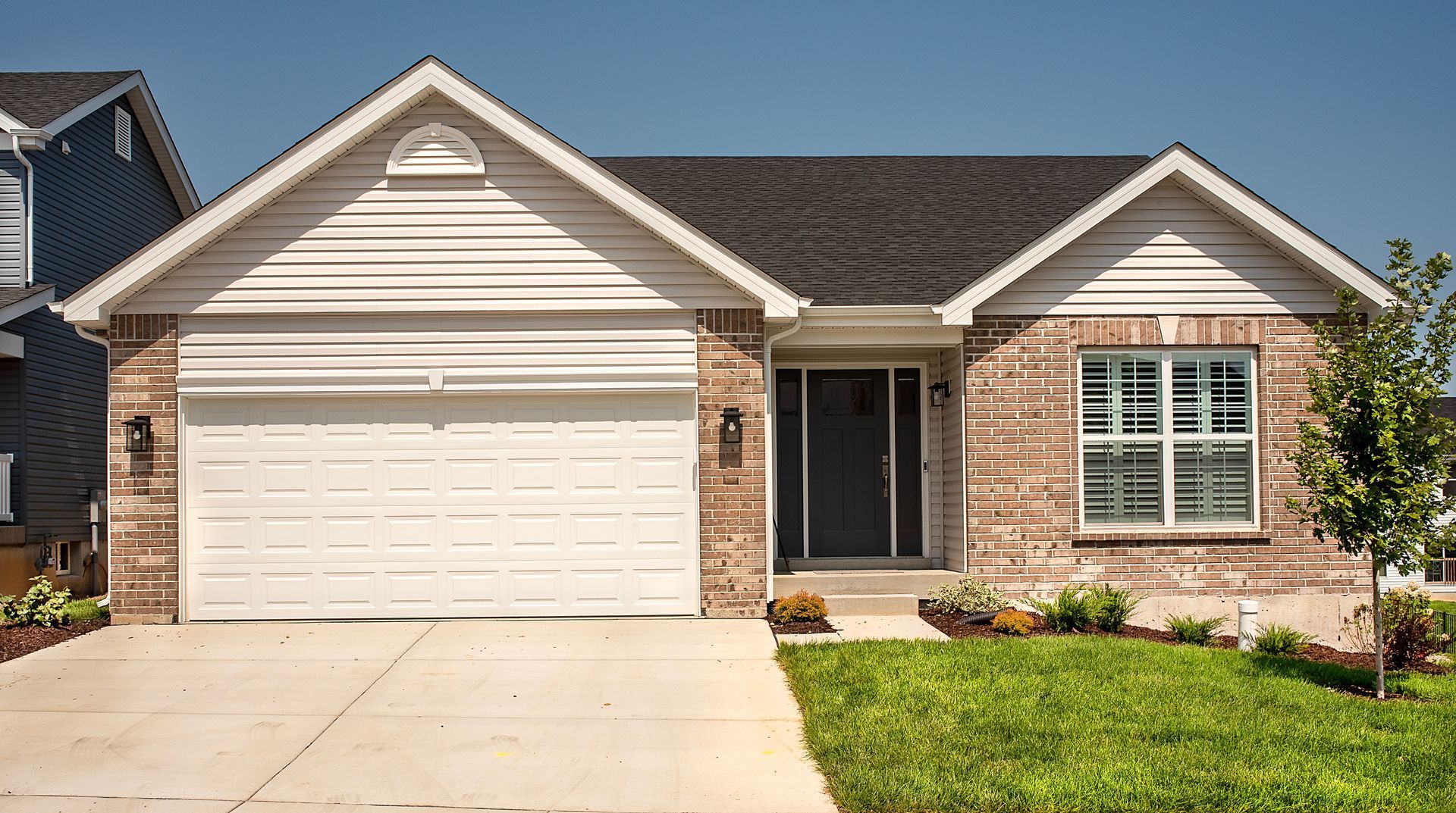 A brick house with a white garage door and a gray roof.