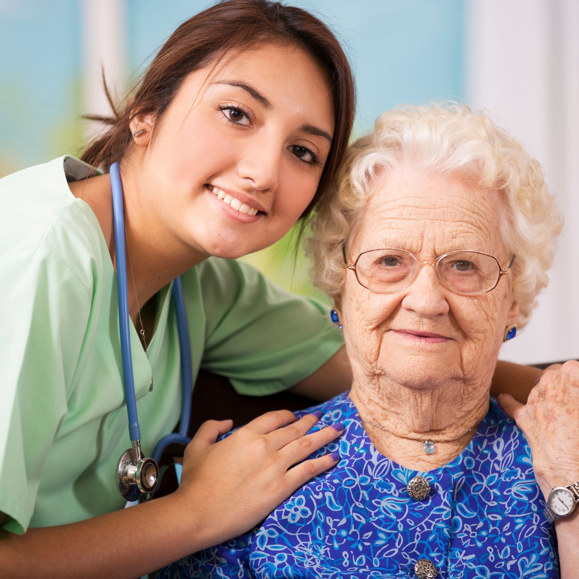 A nurse is posing for a picture with an elderly woman