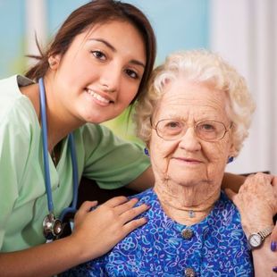 A nurse is putting her arm around an elderly woman