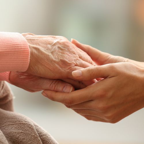A woman is holding the hand of an older woman.