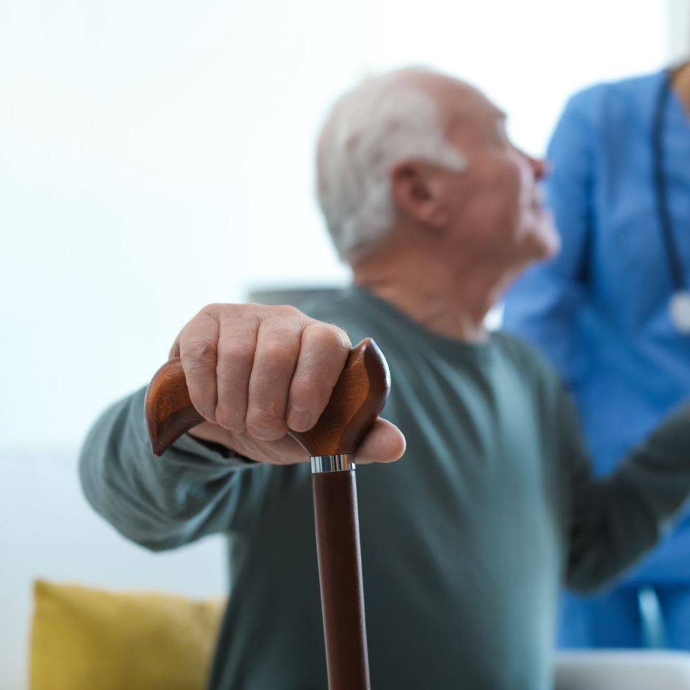 An elderly man is holding a cane in front of a nurse