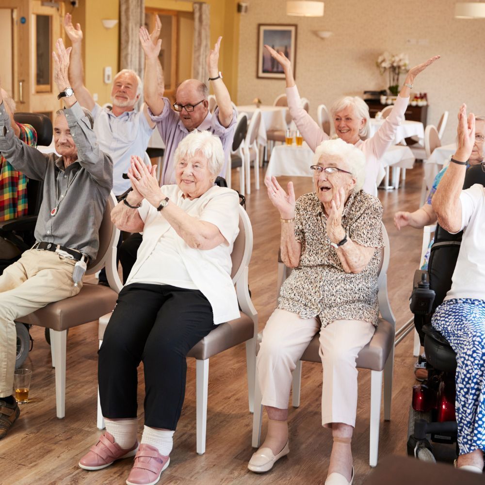 A group of people sitting in chairs with their hands in the air