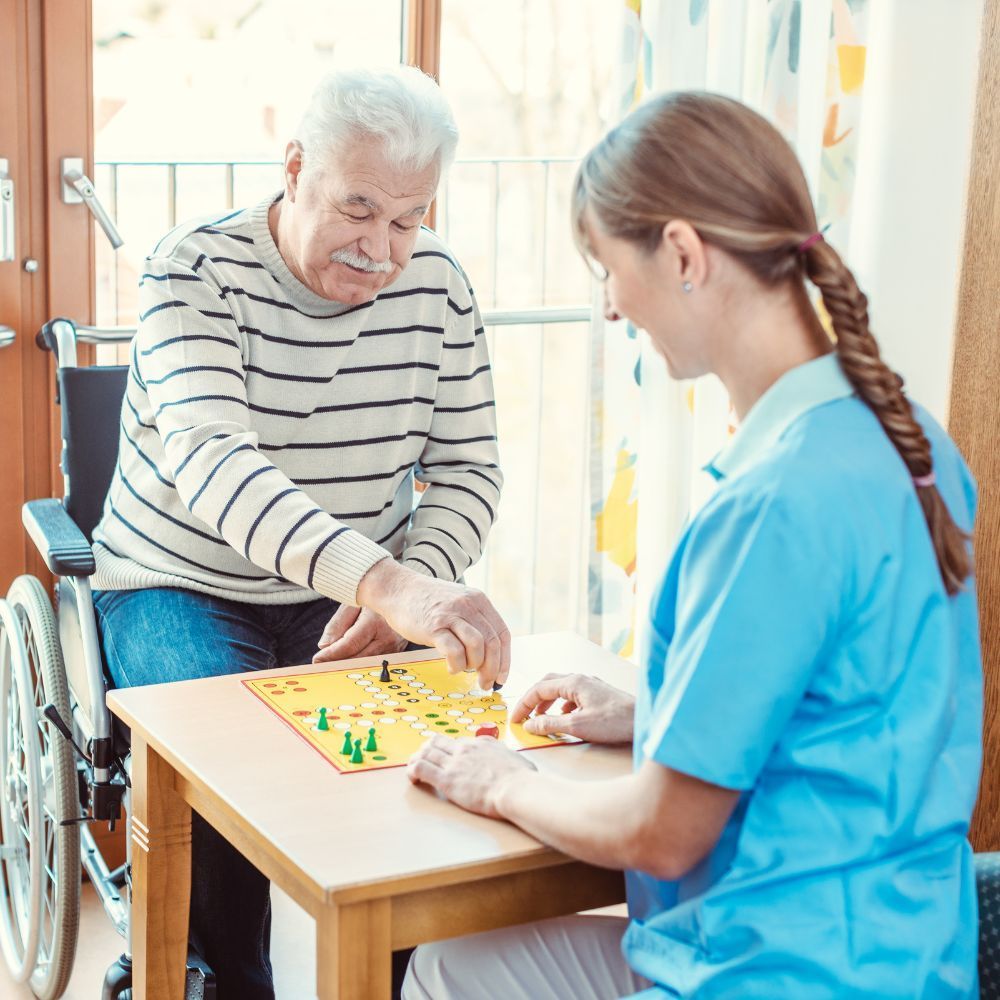 A man in a wheelchair is playing a board game with a nurse