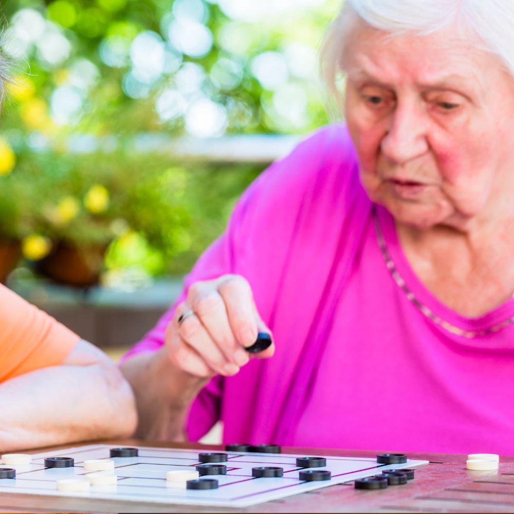 A woman in a pink shirt is playing a board game with a child.