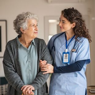 A nurse is helping an elderly woman with a cane.