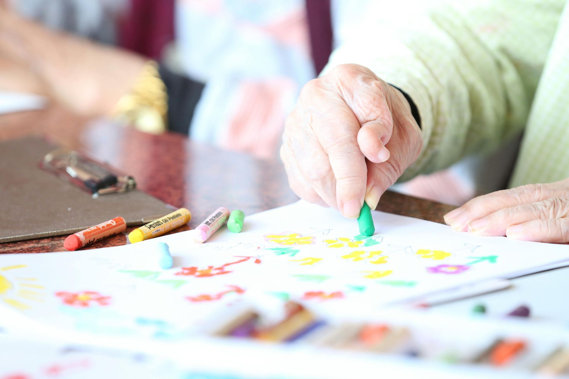 A person is drawing with crayons on a piece of paper.