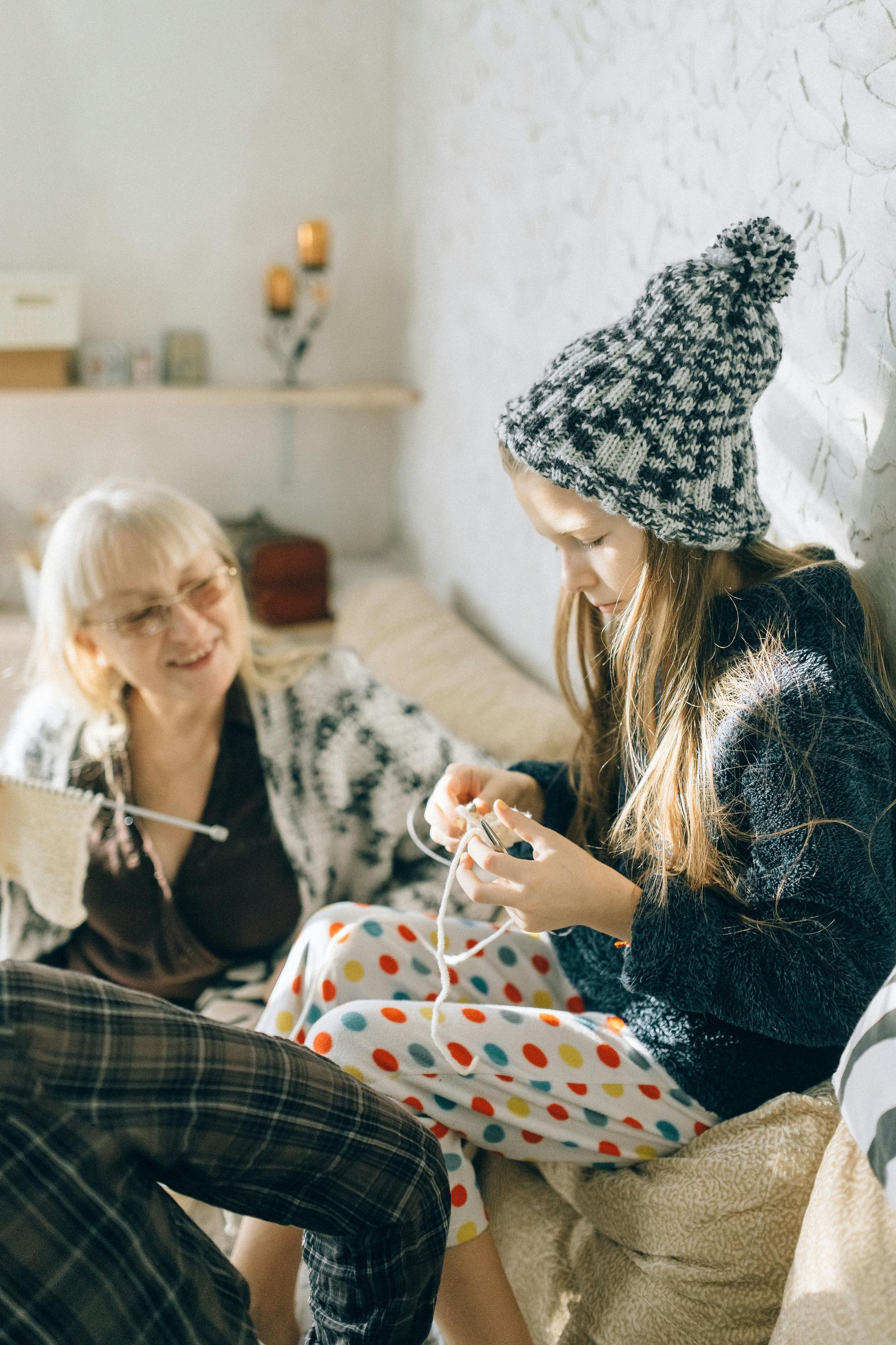 A family is sitting on a couch knitting together.