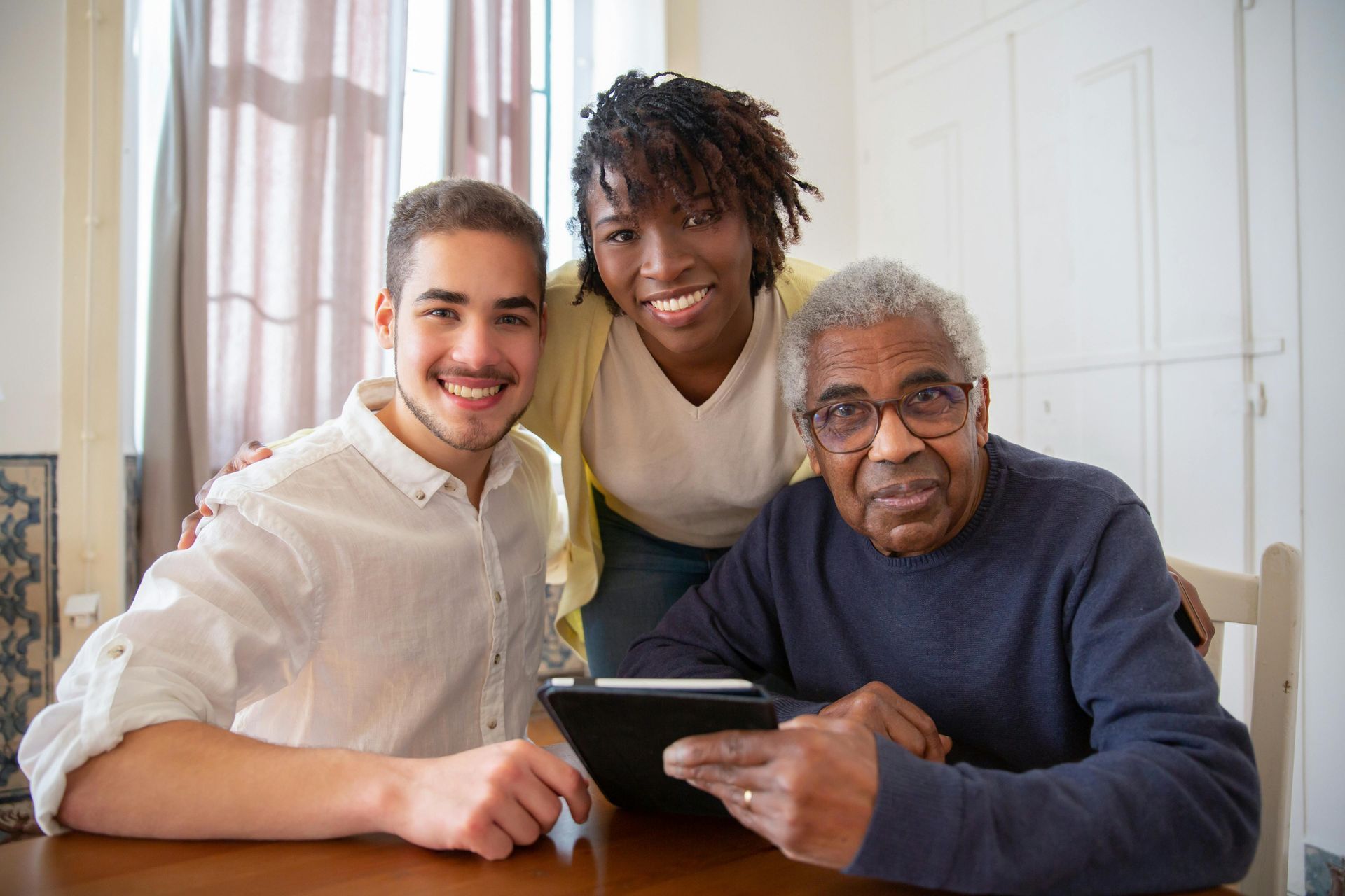 A group of people are sitting at a table looking at a tablet.