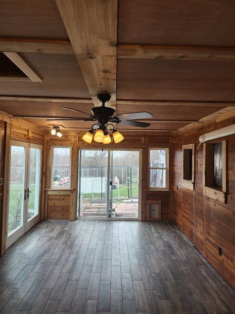 An empty room with a ceiling fan and sliding glass doors.