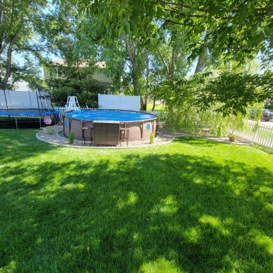 A large swimming pool is sitting in the middle of a lush green yard.