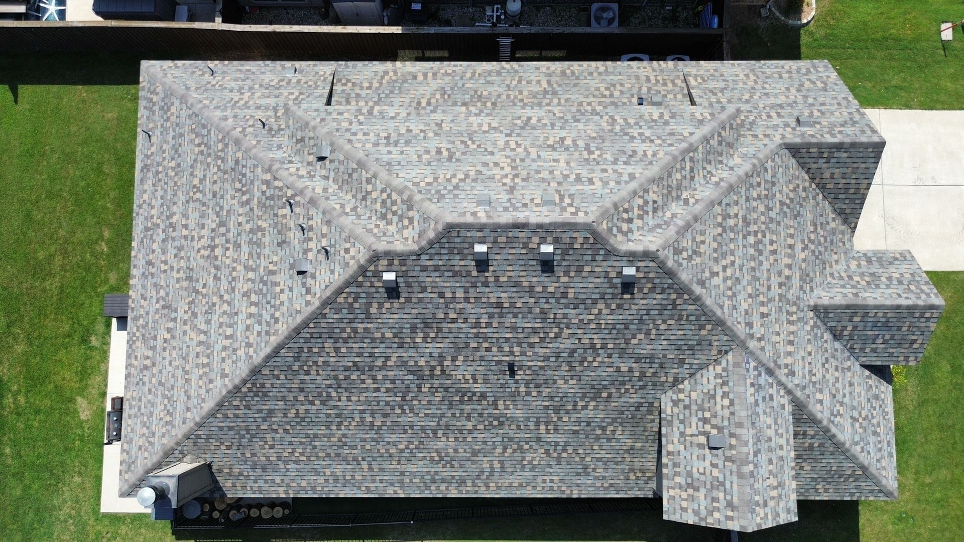 Overhead view of a house with a grey shingle roof on green grass.