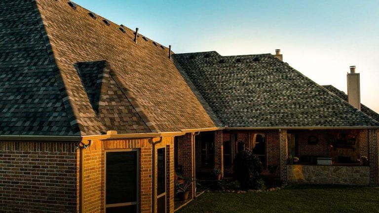 Brick house with dark roof and sunny glow.