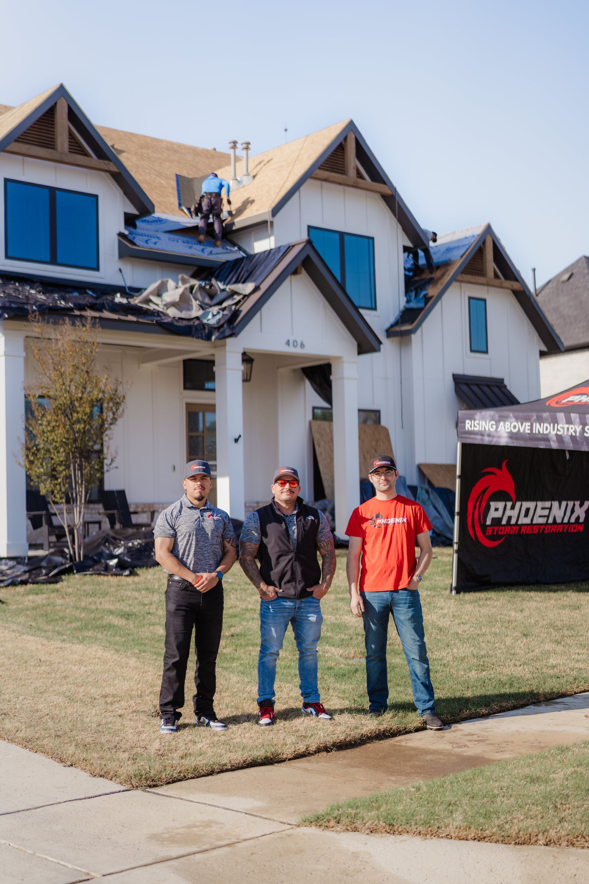 Three roofers in front of a house under construction with the Phoenix logo in the background.