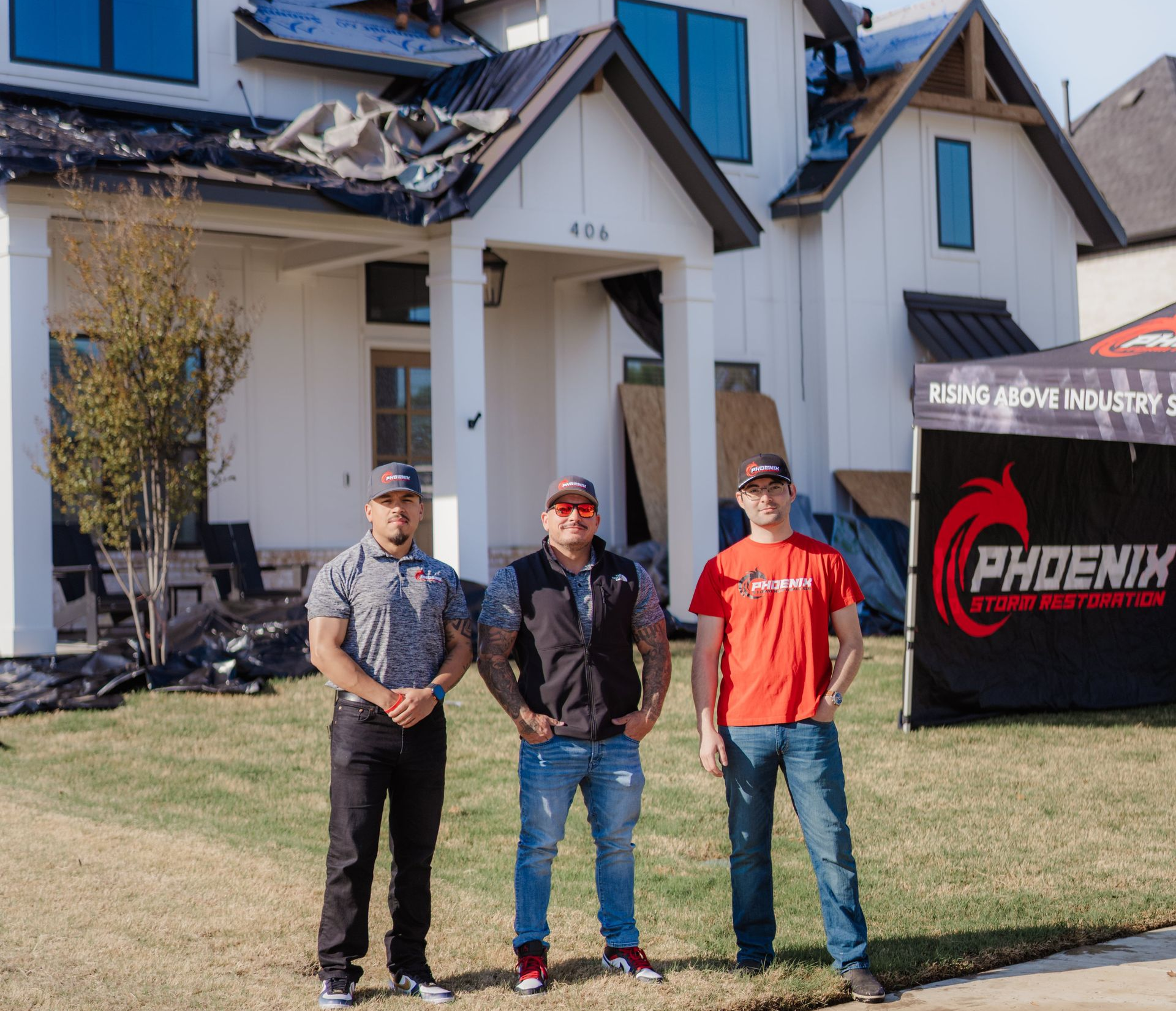Three men in front of a damaged house; Phoenix Storm Restoration banner.
