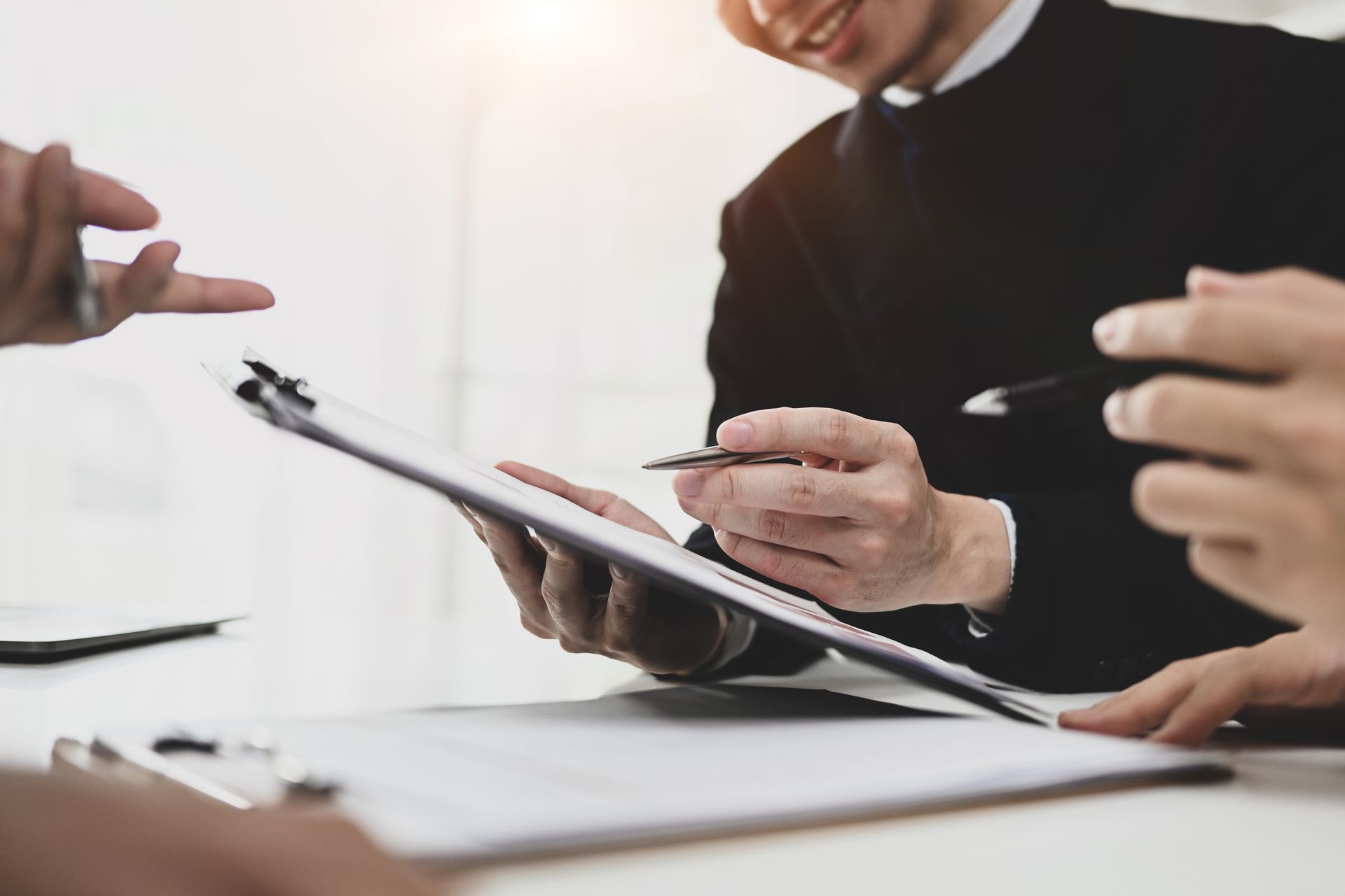 Businesspeople reviewing documents, one pointing, smiling in office.
