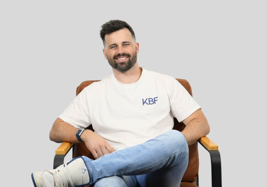 A man with a beard is standing with his arms crossed and smiling.