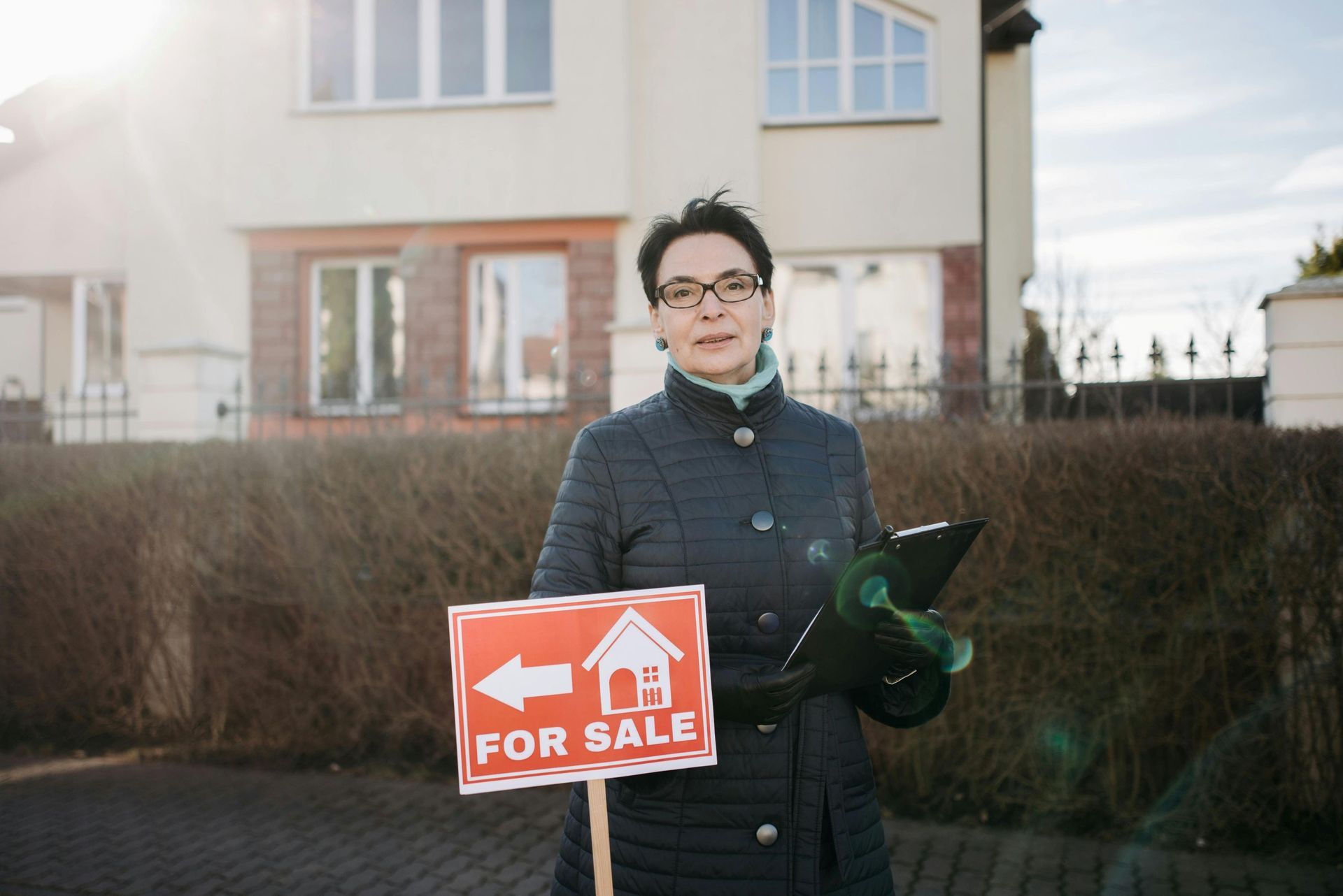 real estate agent with for sale sign: Brisbane brokers help homebuyers with loans for second home.