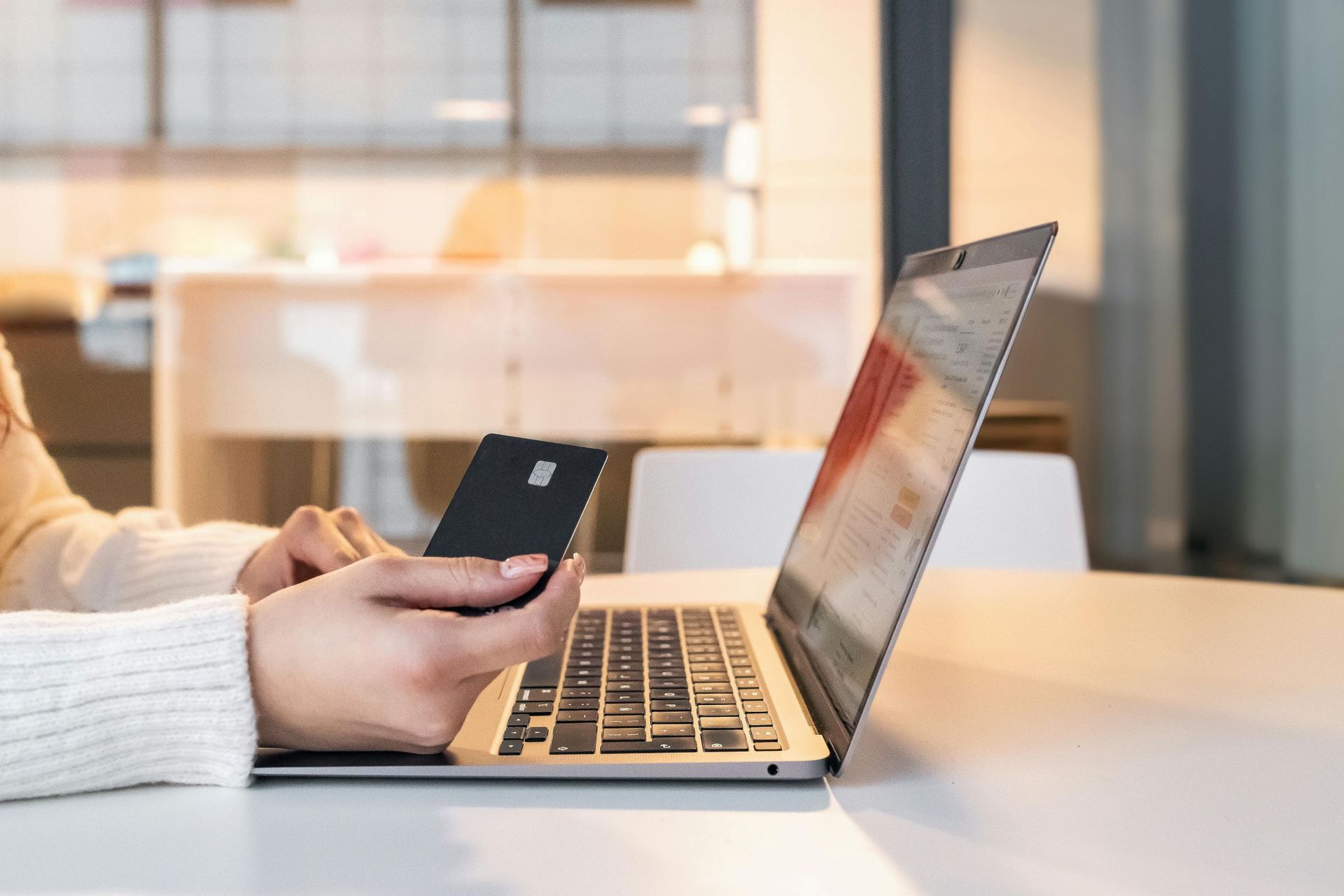 a person holding a credit card, while processing payment over a laptop