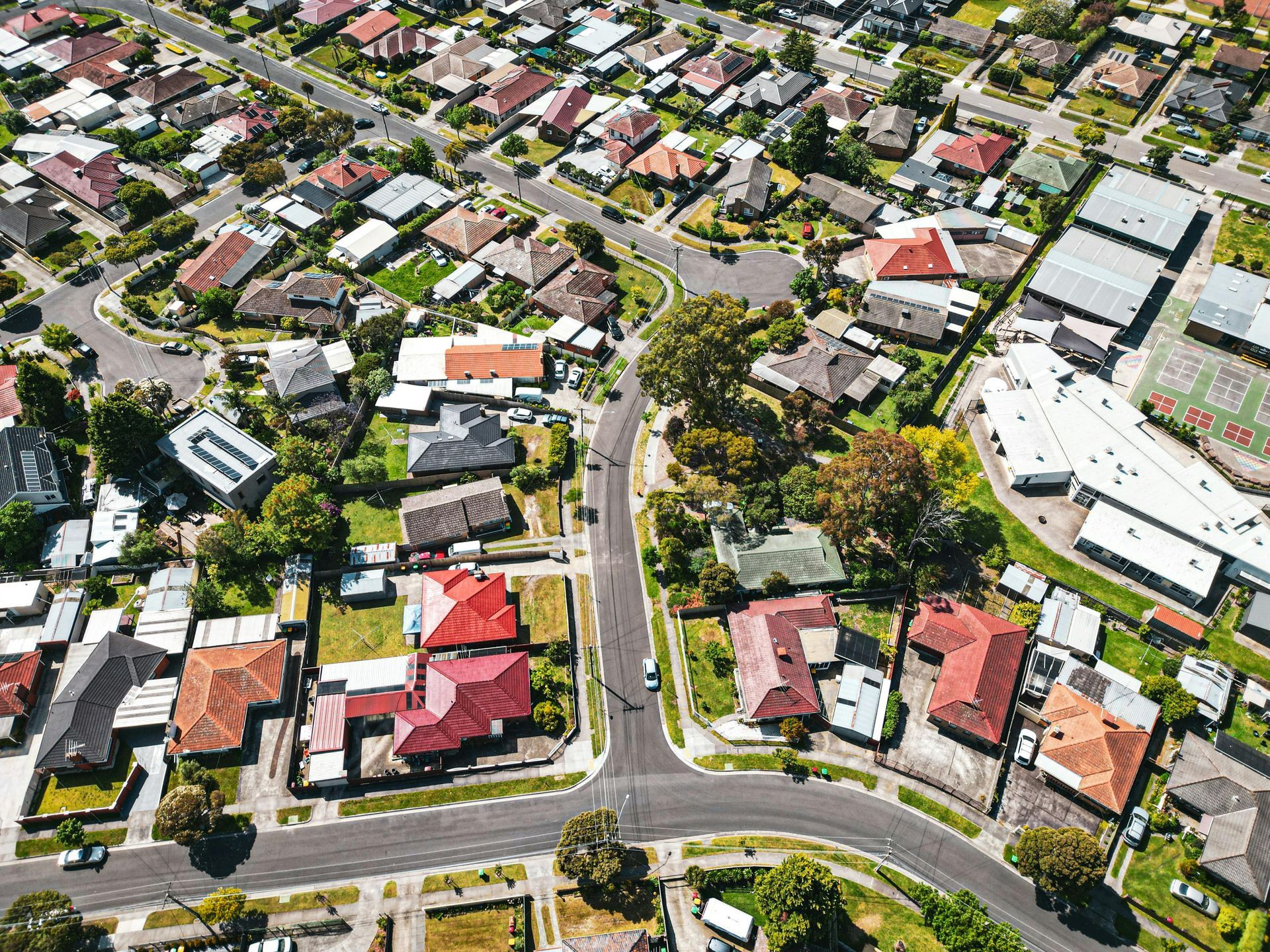 Aerial view of a suburban neighborhood with houses, streets, and a large curved road intersection.