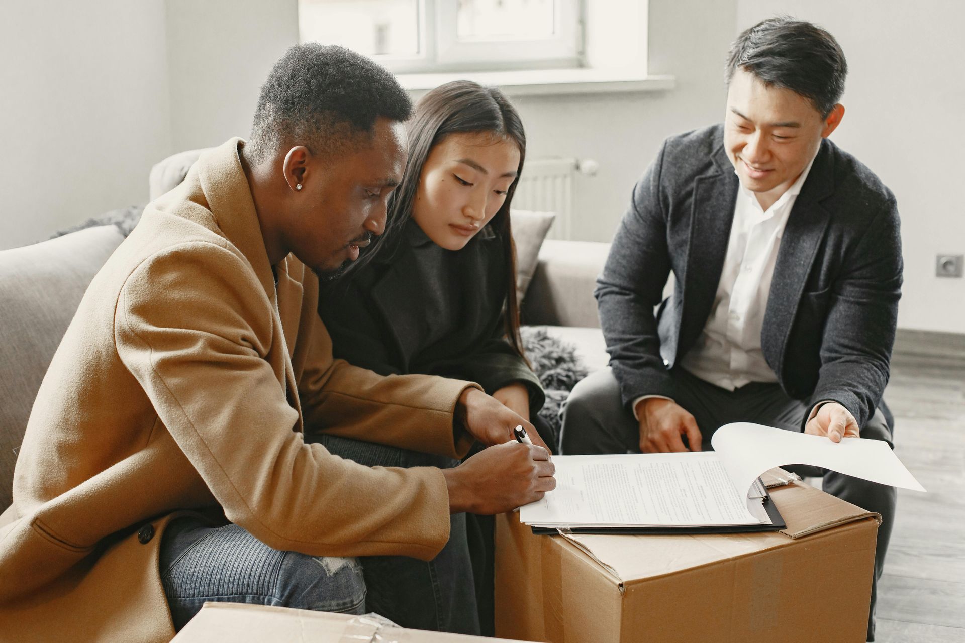 Three people collaborating over documents at a table in a bright office