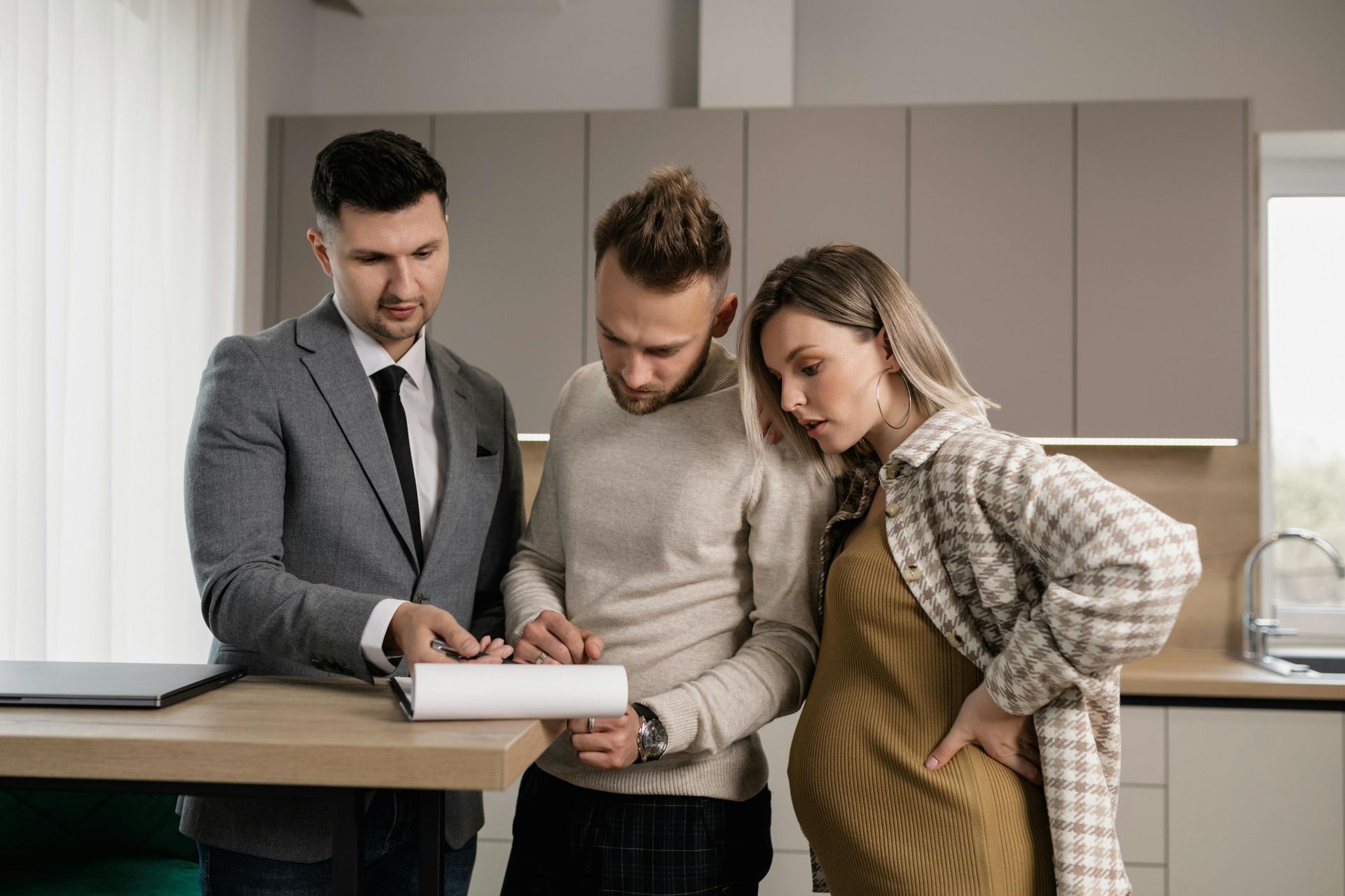 Three people reviewing a document together in a modern kitchen