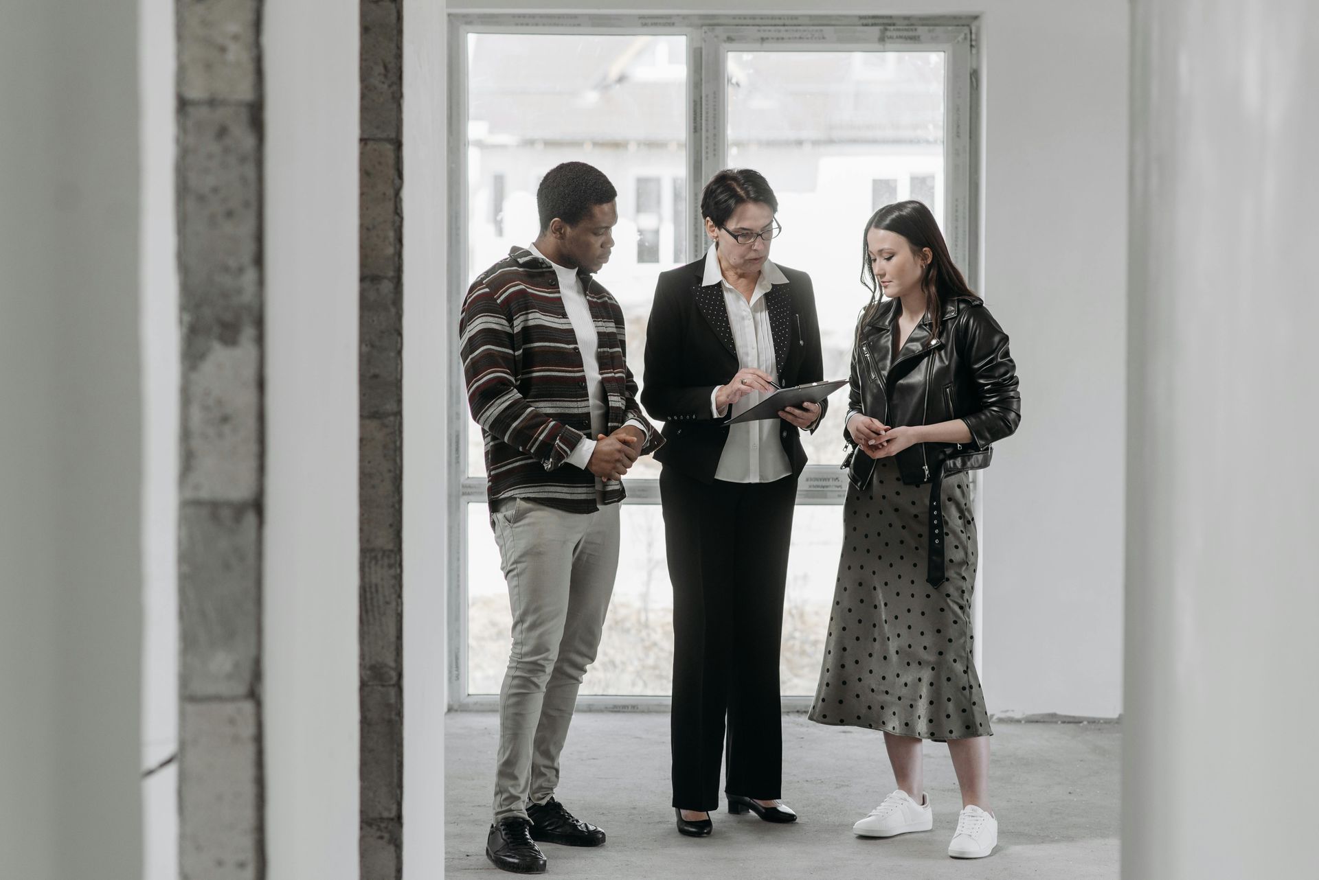 Three coworkers discussing a document in a bright office doorway