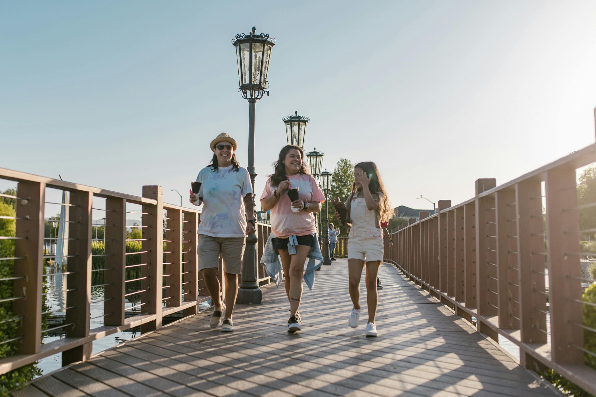 Three persons walking on a footbridge.