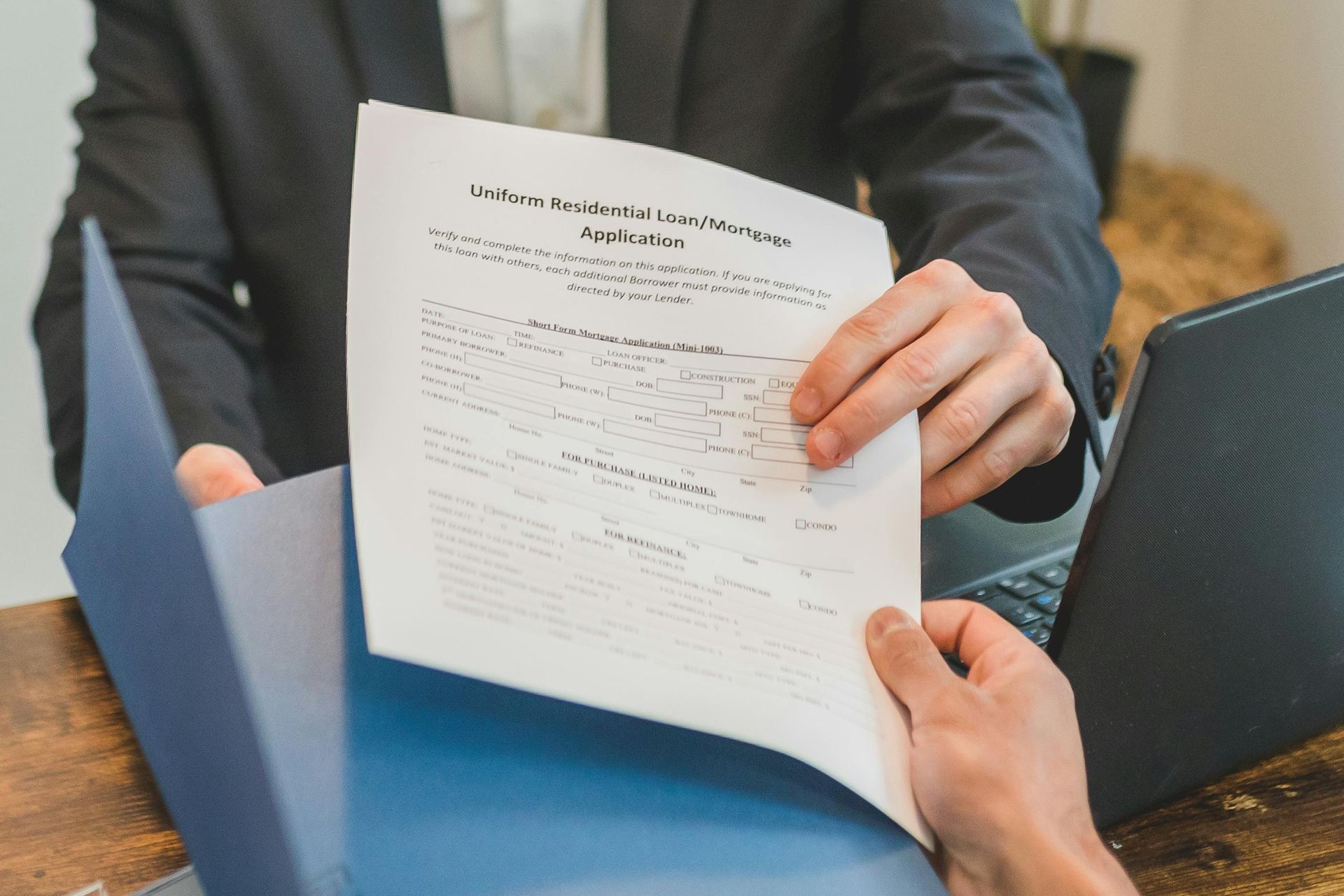 Two people reviewing a document over a blue folder on a table, one holding the paper.