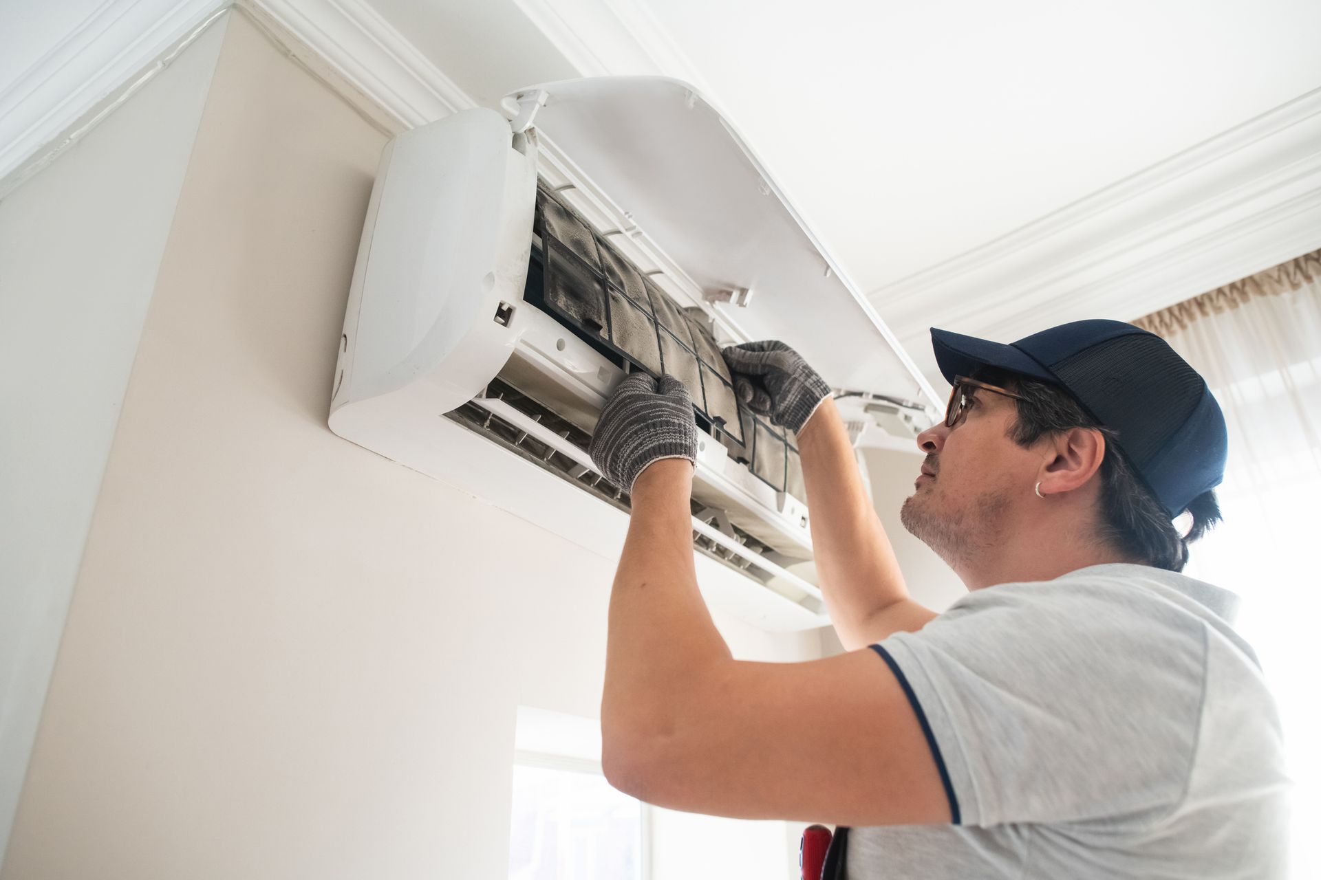 Technician with glasses doing air conditioner maintenance as part of professional AC repair service.