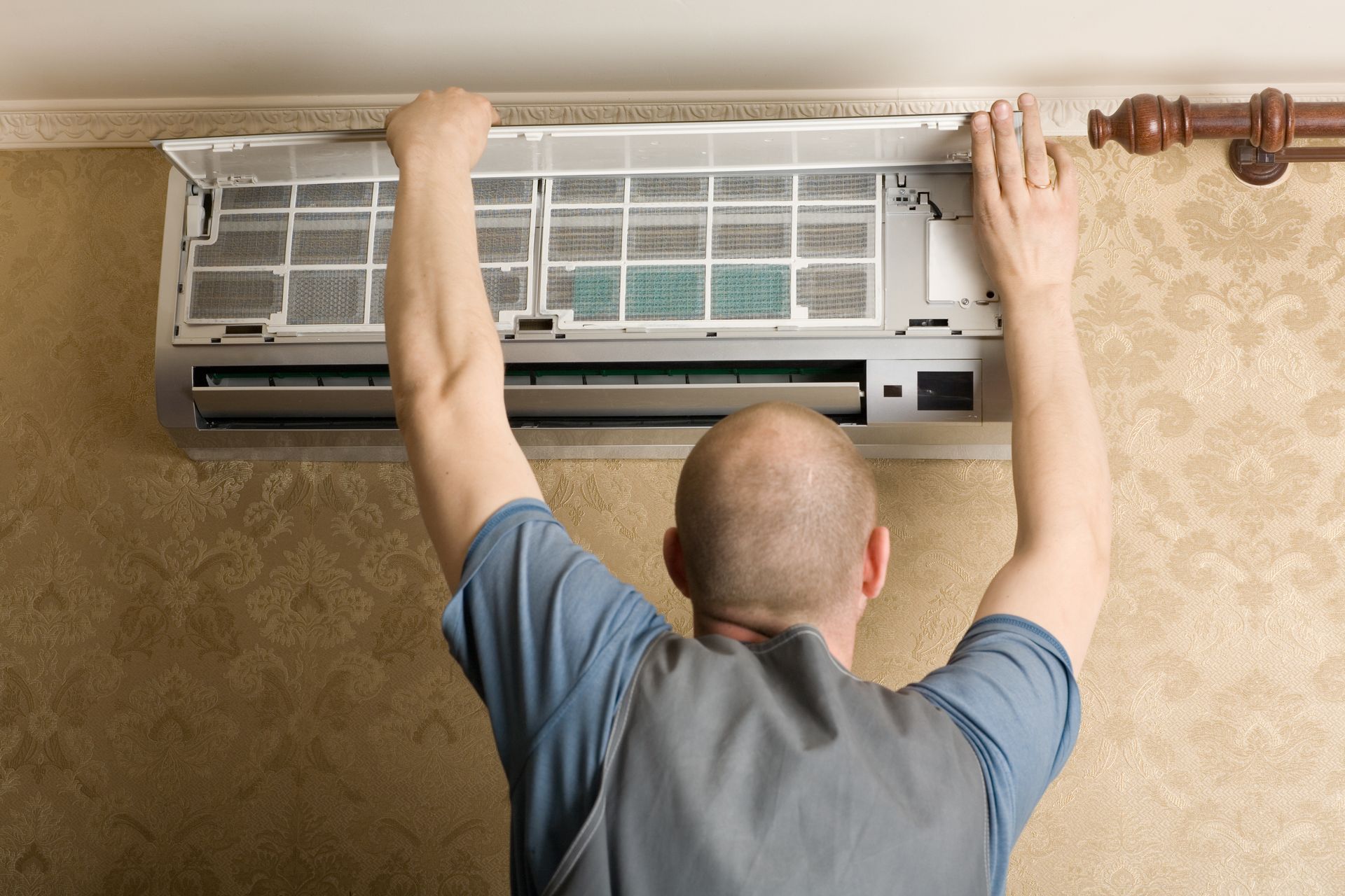 Man installs a new air conditioning system inside a room, placing the filter on its inside.