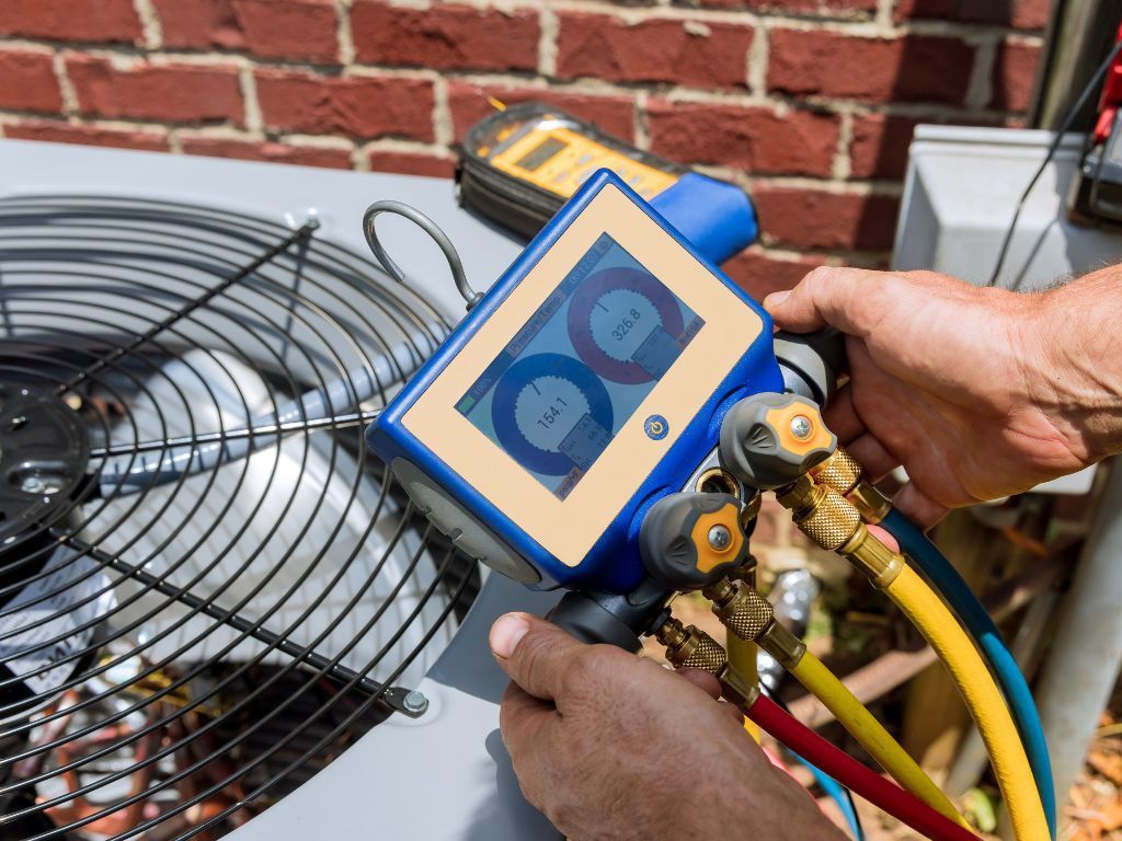 A person is working on an air conditioner with a hose attached to it.