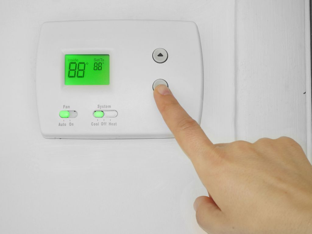 A person is pressing a button on a thermostat.