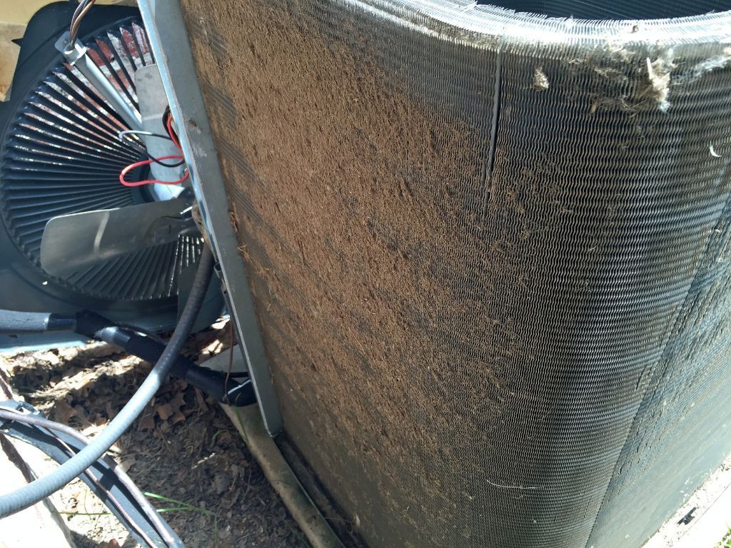 A close up of a dirty air conditioner with a fan attached to it.