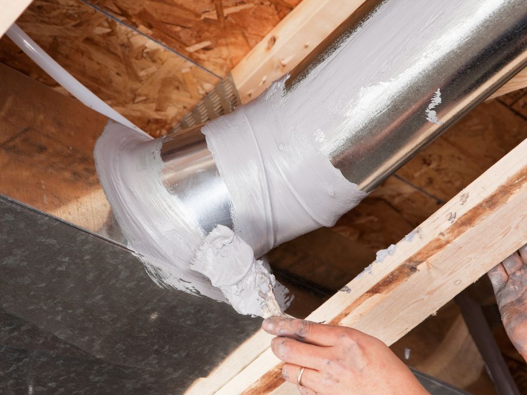 A person is applying cement to a metal pipe