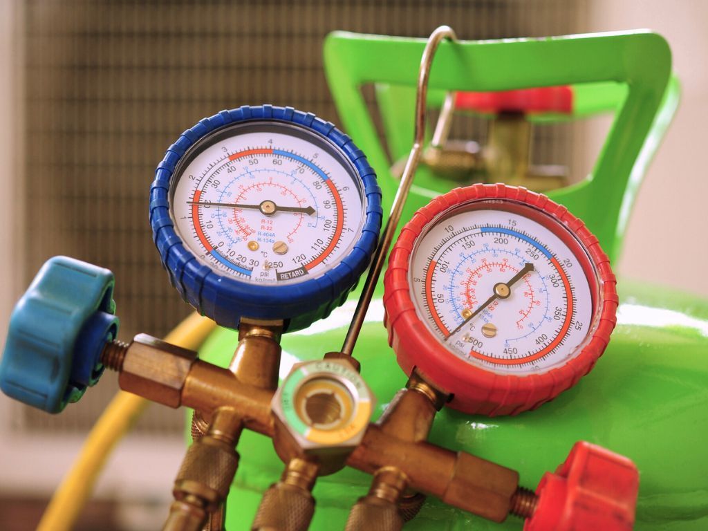 Two pressure gauges are sitting on top of a green tank.