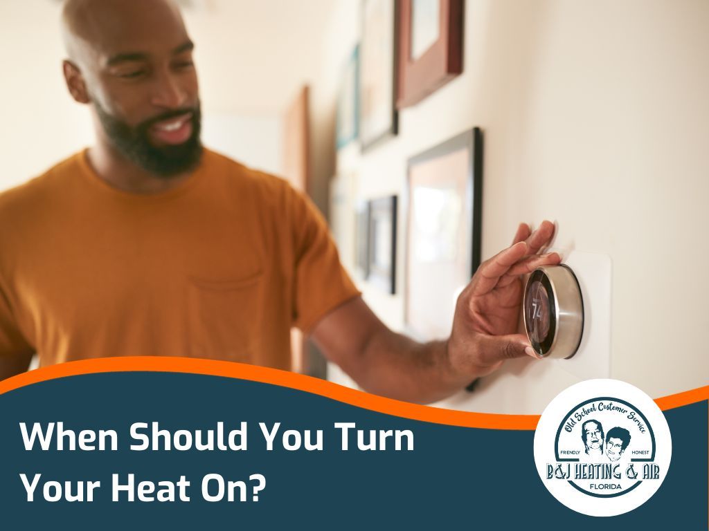 A man is adjusting a thermostat on a wall.