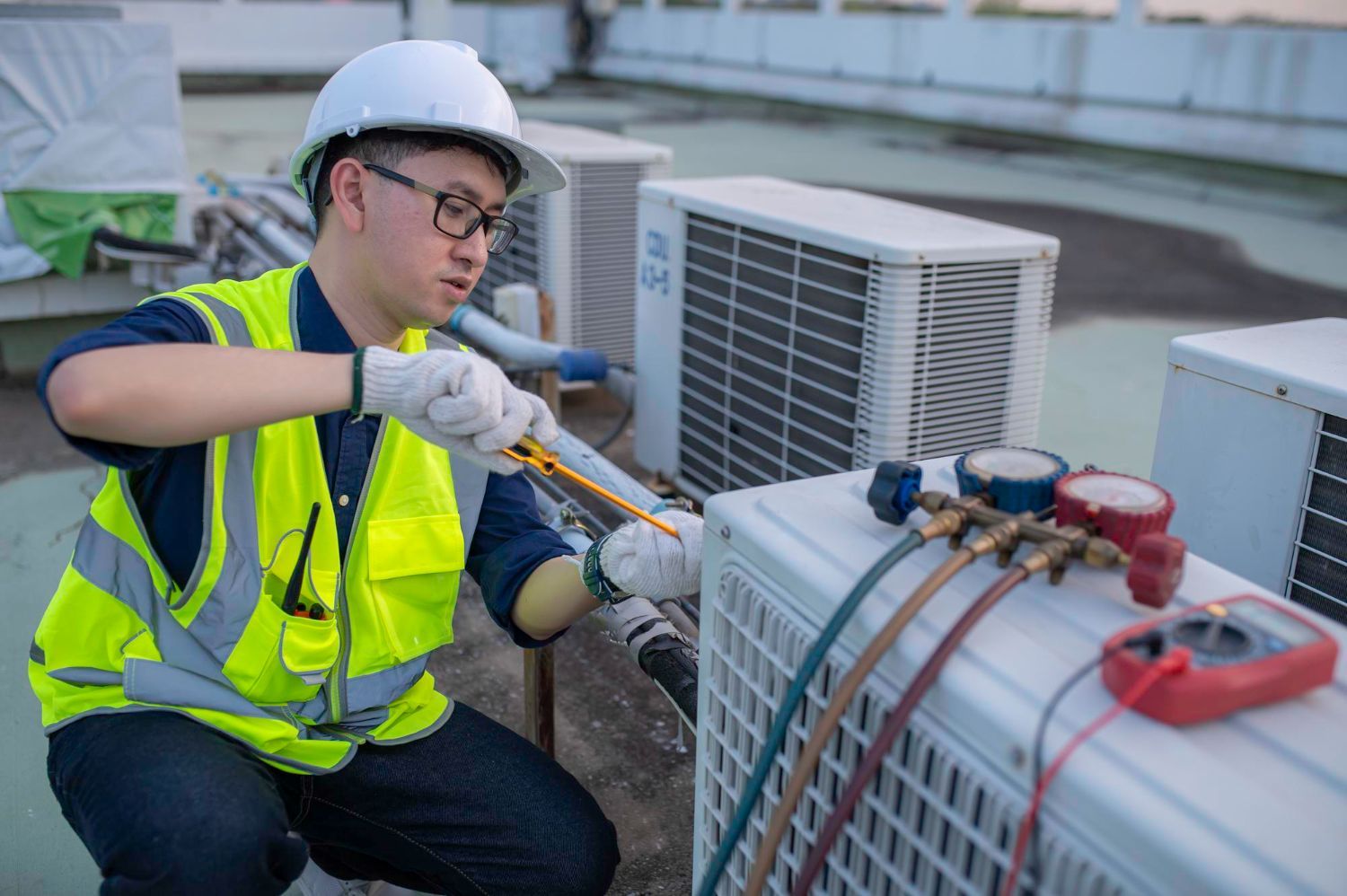 A man is working on an air conditioner on a rooftop.