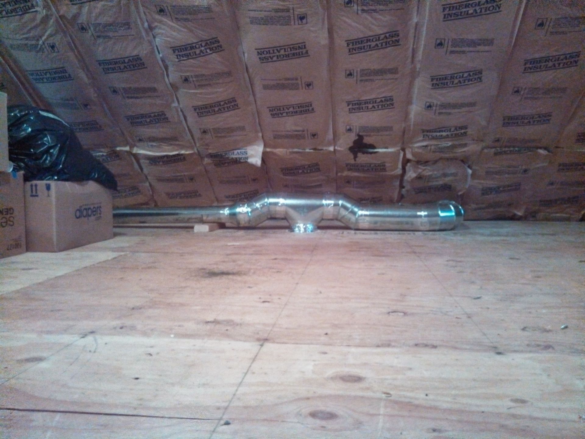 An attic with boxes and pipes on the floor