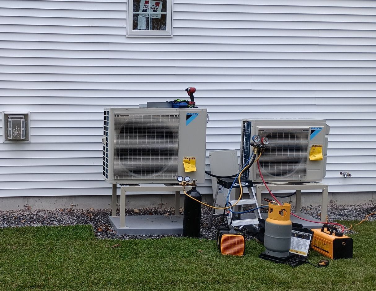 Two air conditioners are being installed on the side of a house.