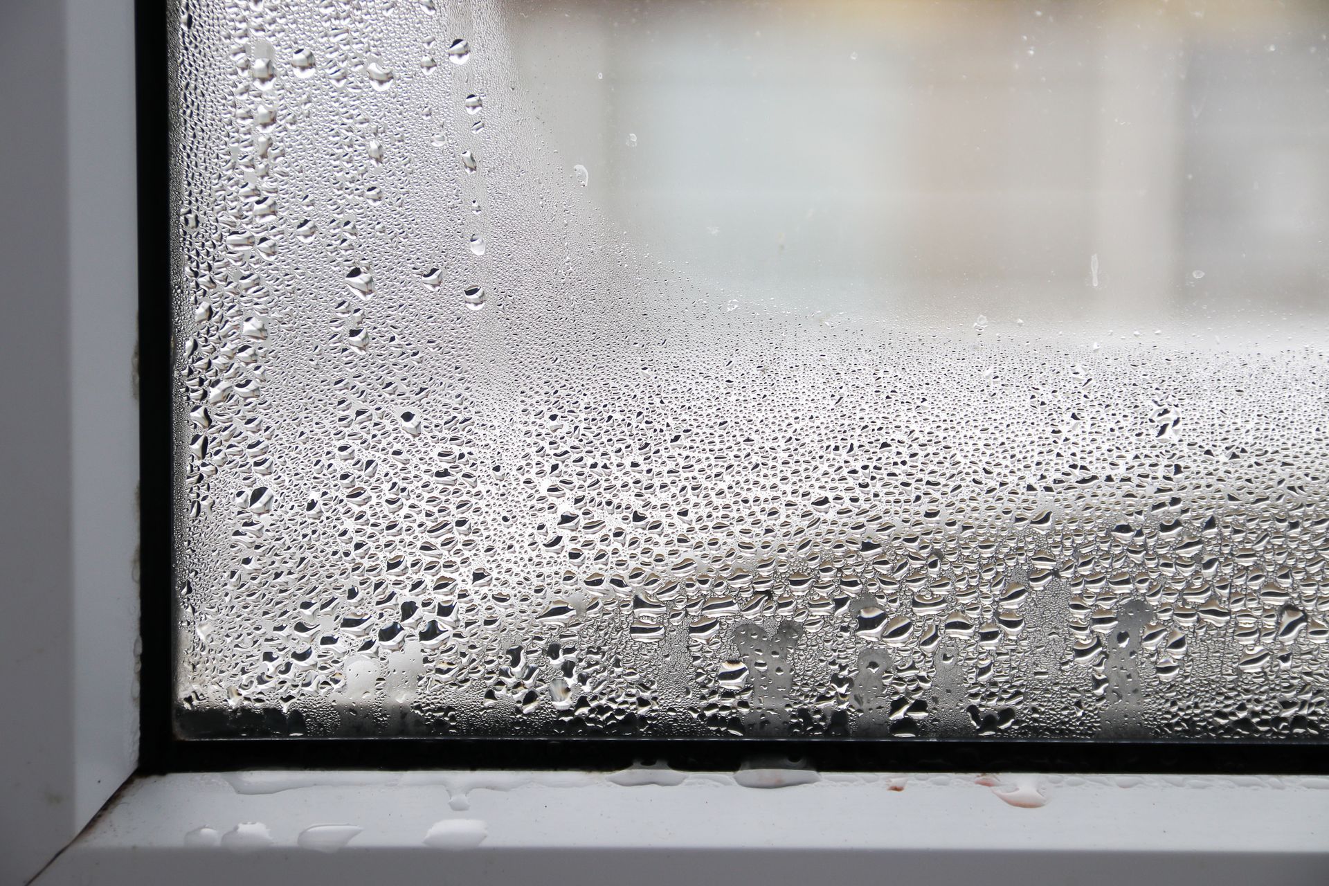 Window with heavy condensation on the glass, forming water droplets.