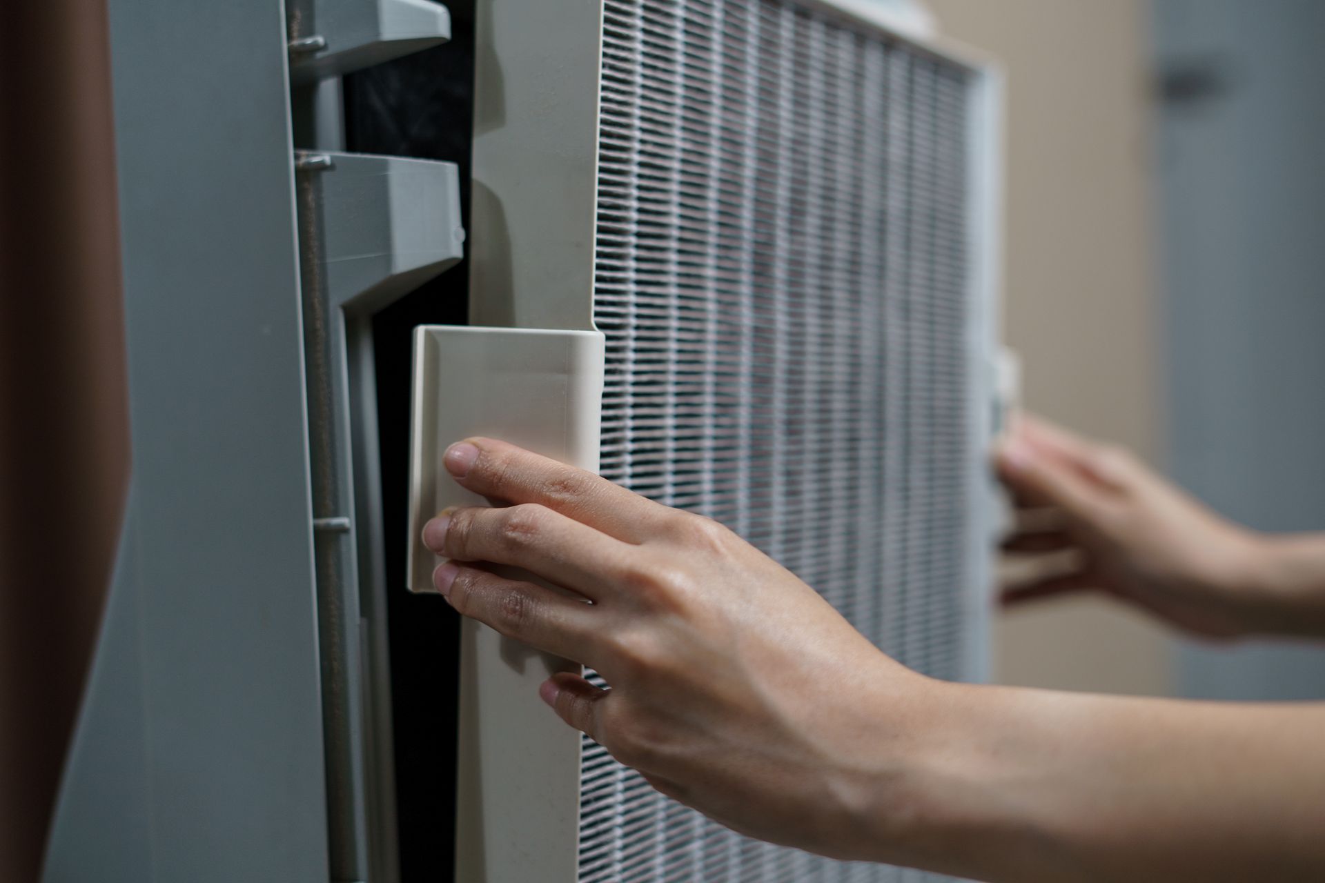 A person is changing a filter on an air conditioner.
