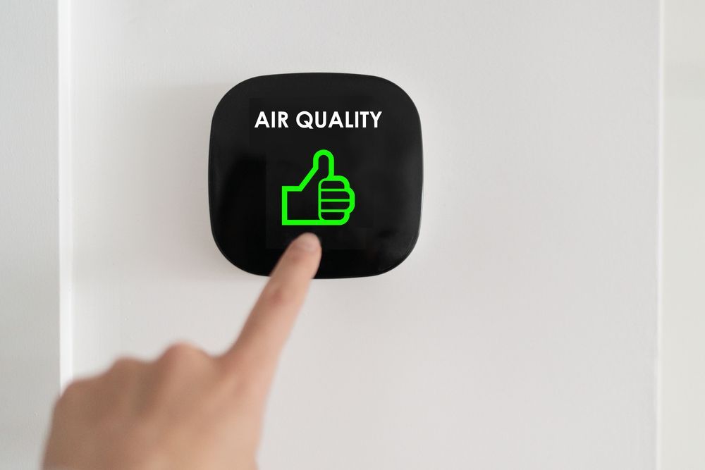 A person is pressing a button on a wall that says `` air quality ''.