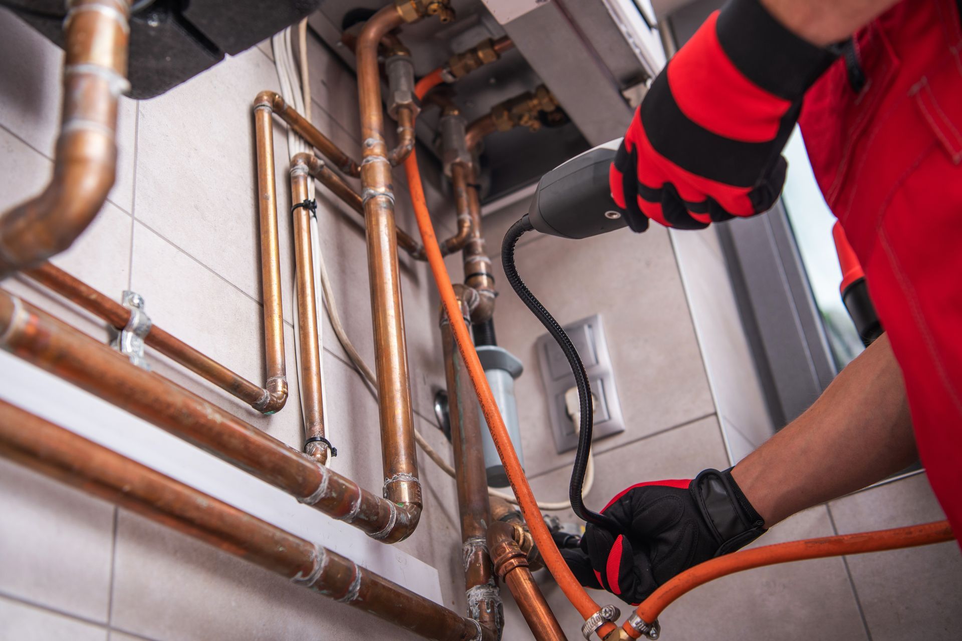 A plumber is working on a copper pipe with a drill.