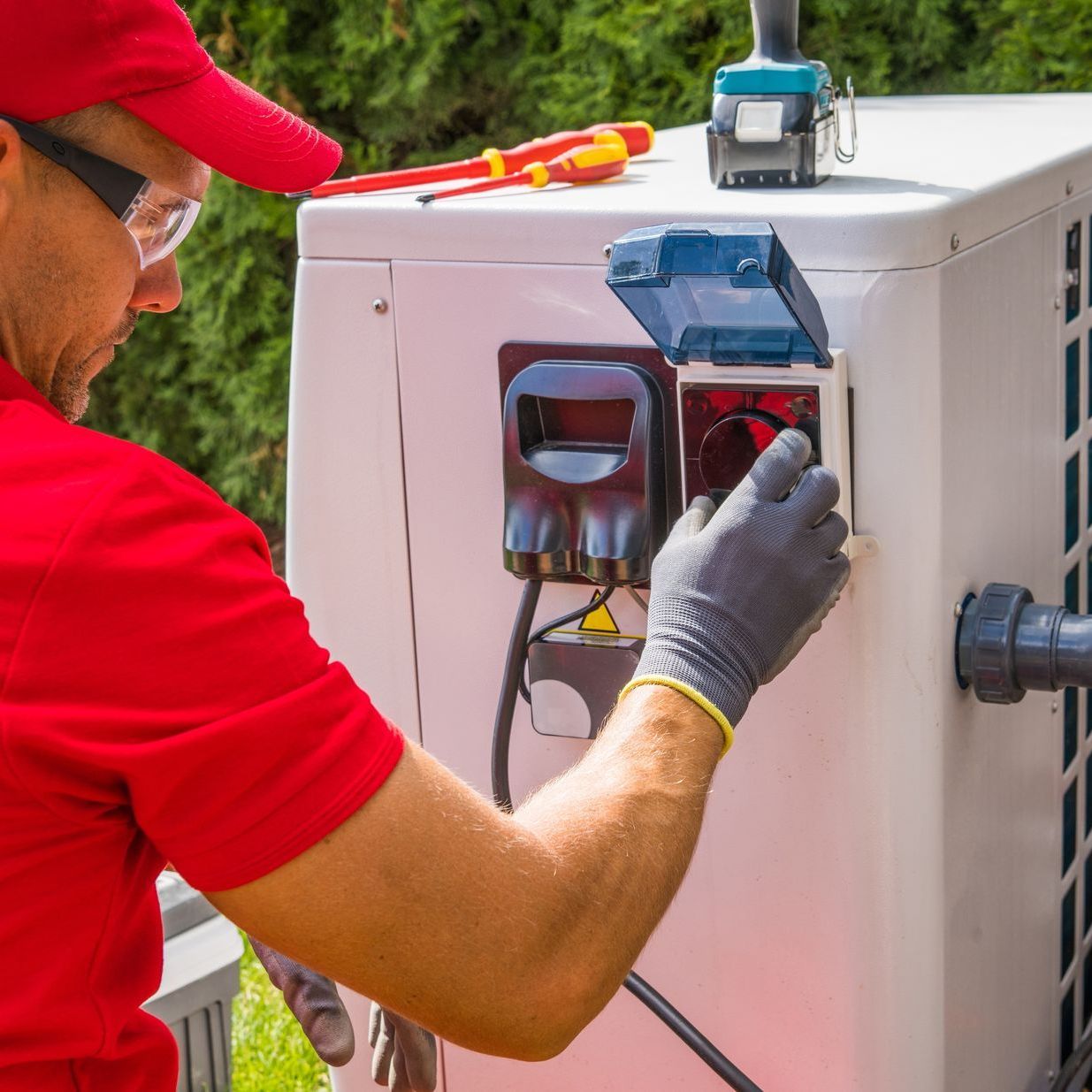 A man in a red shirt is working on a machine.